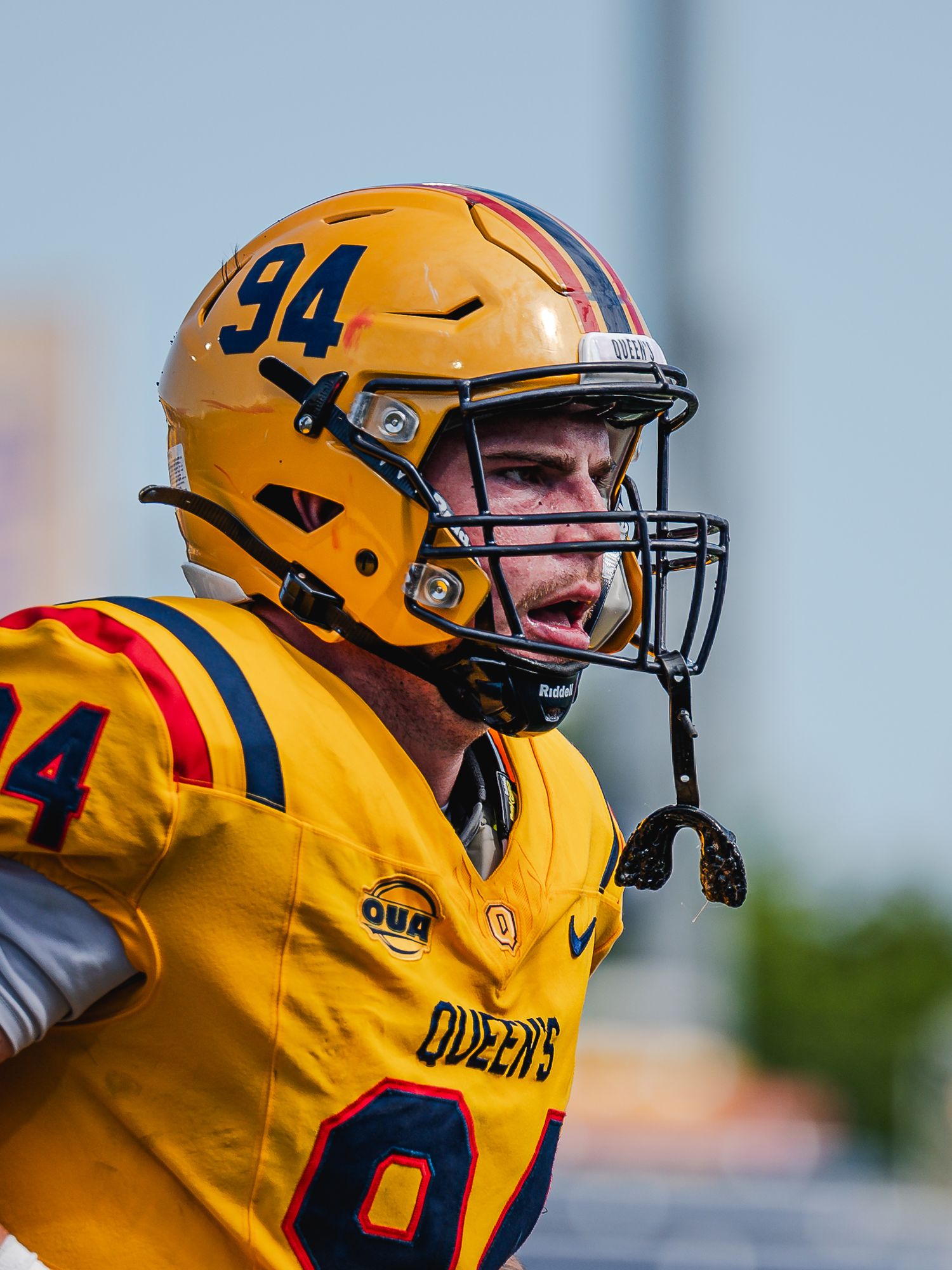 Queen's University number 94 football player in gold helmet.