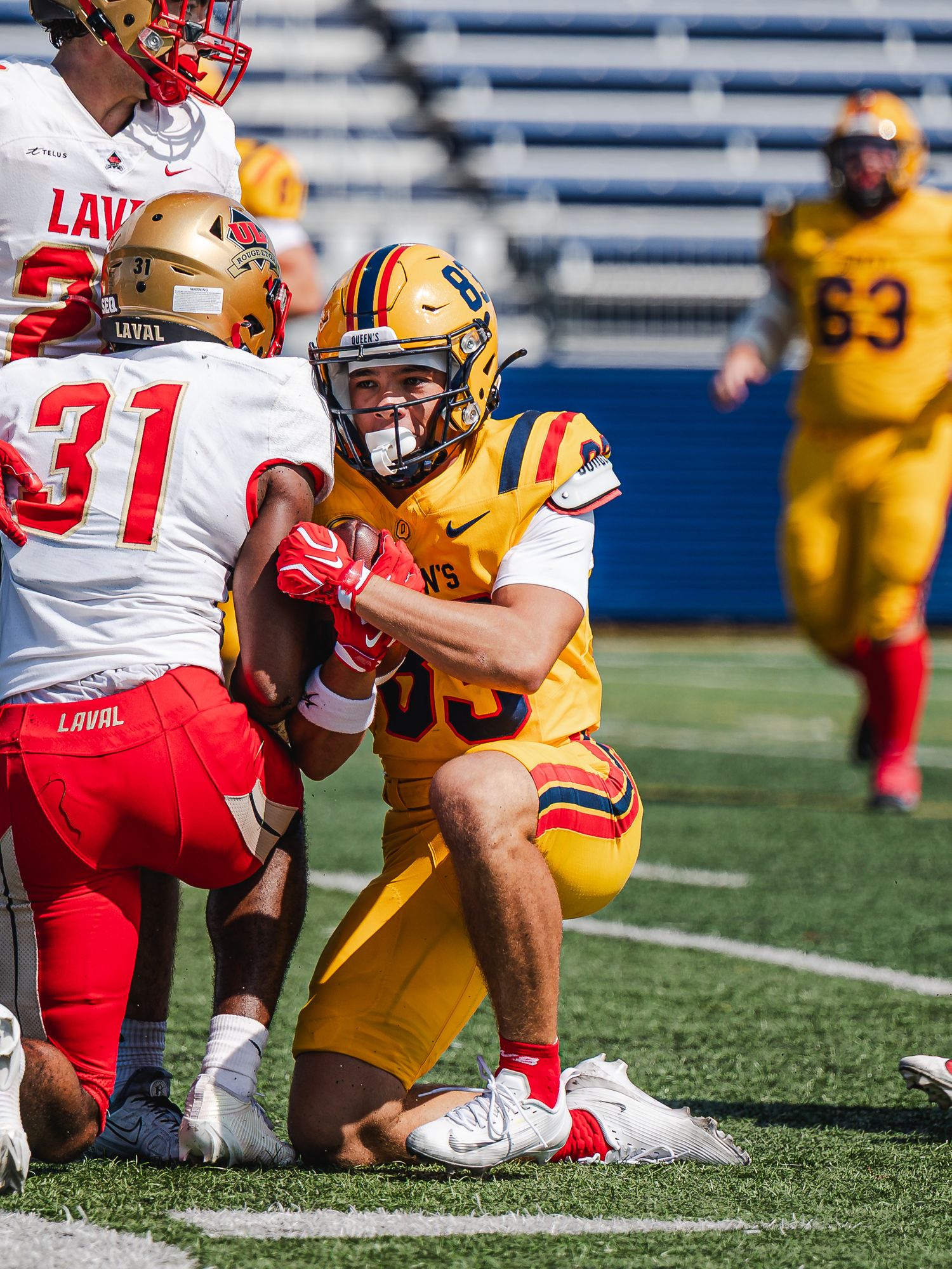 Queen's football player tackles Laval University opponent on field.
