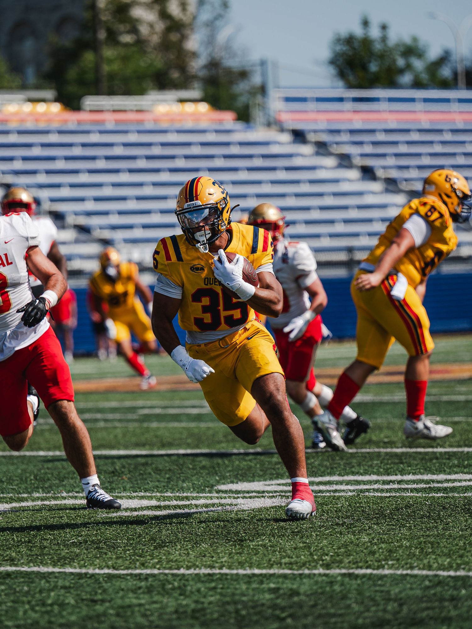 Queen's University number 35 runs with ball during game.