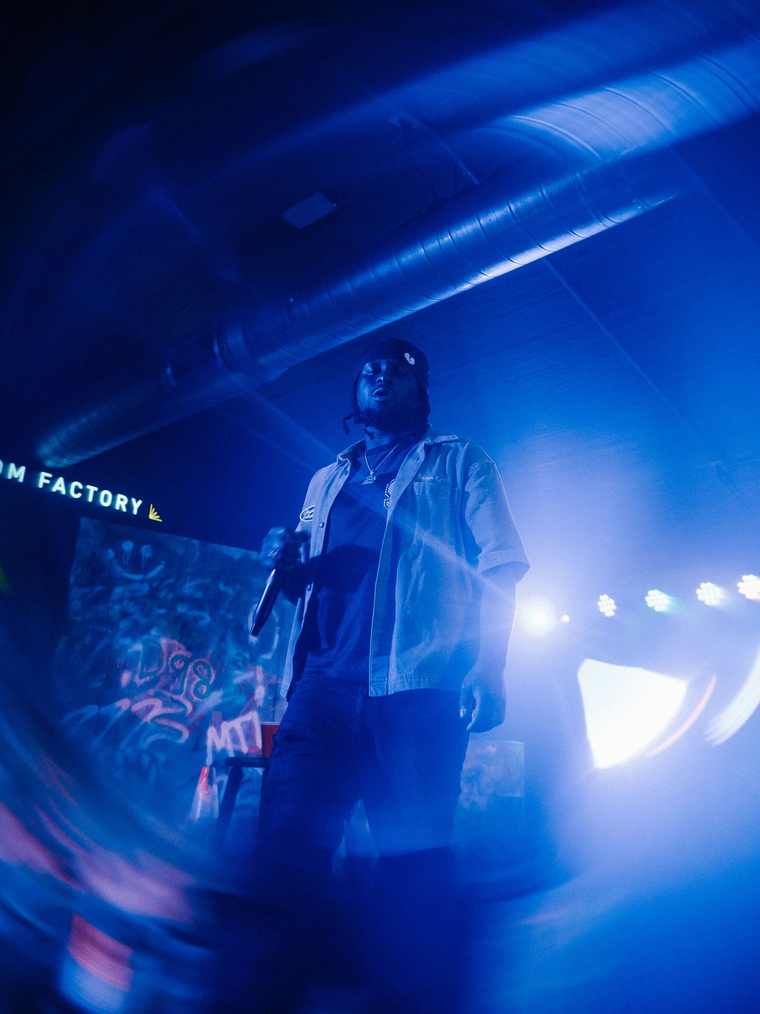 Performer on stage surrounded by dramatic blue lighting at Dream Factory venue.