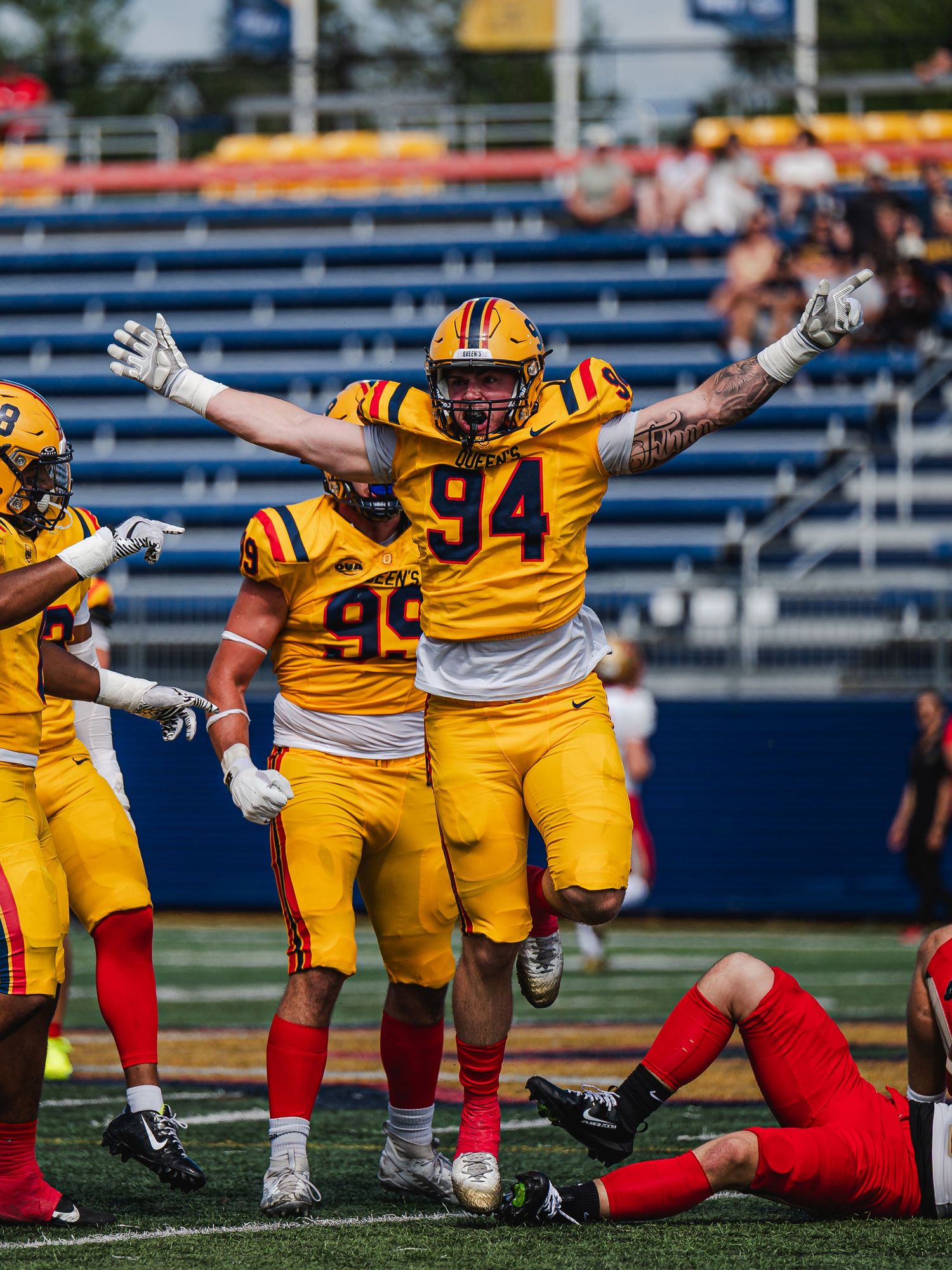 Queen's University number 94 celebrates with arms raised wide.