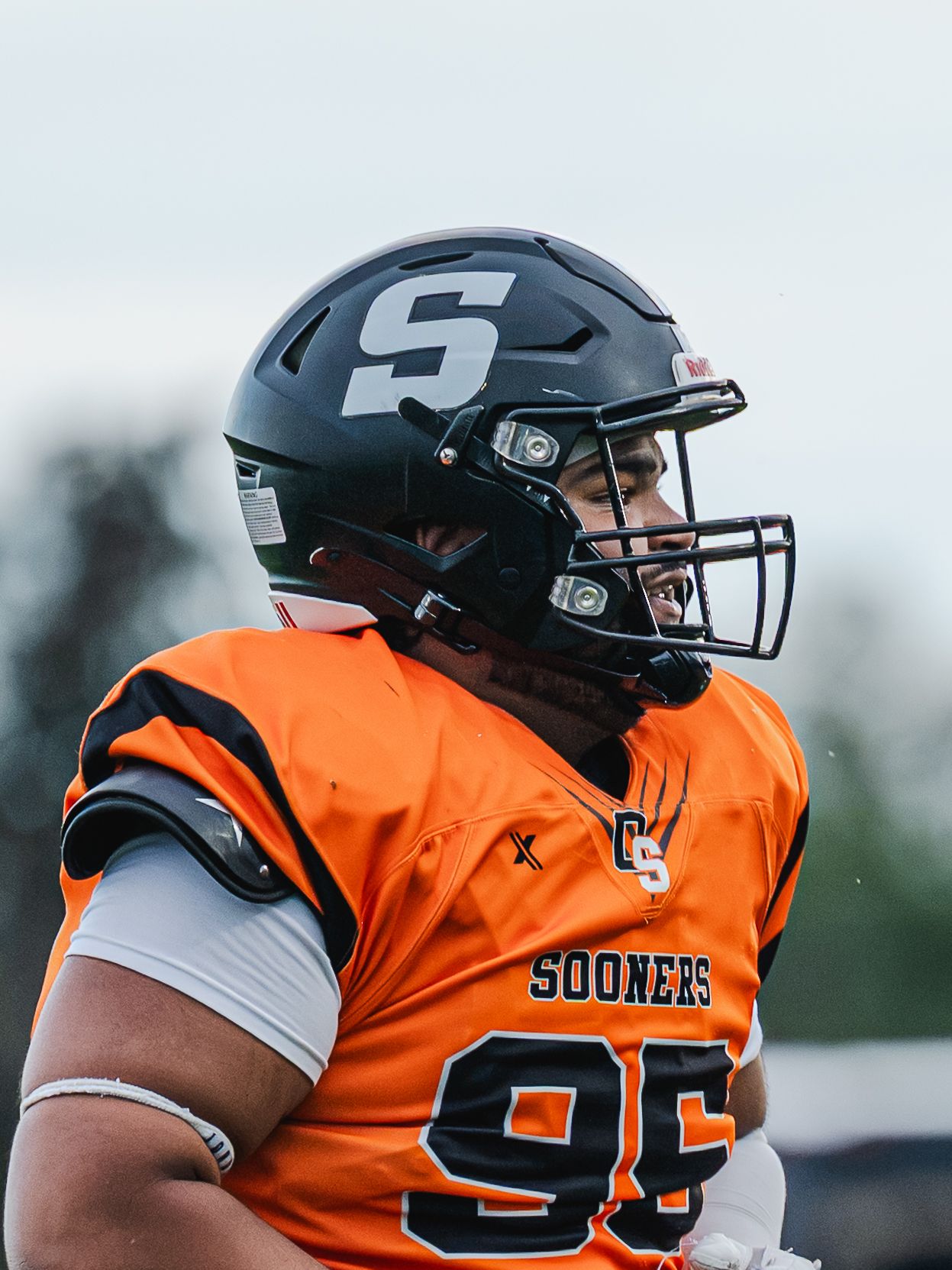 Football player in orange Sooners jersey number 95 wearing black helmet during a game.