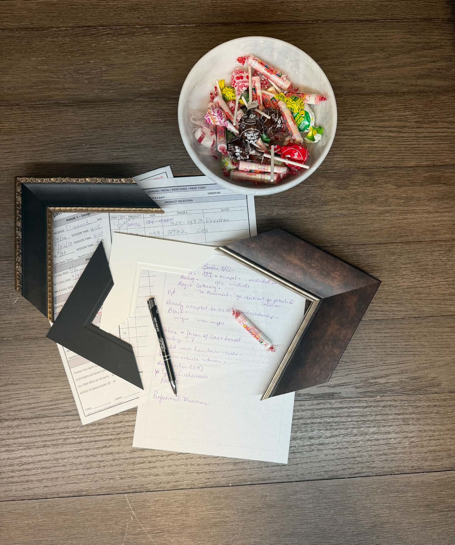 Wedding planning desk with handwritten note cards, a pen, decorative box, and bowl of wrapped candy.