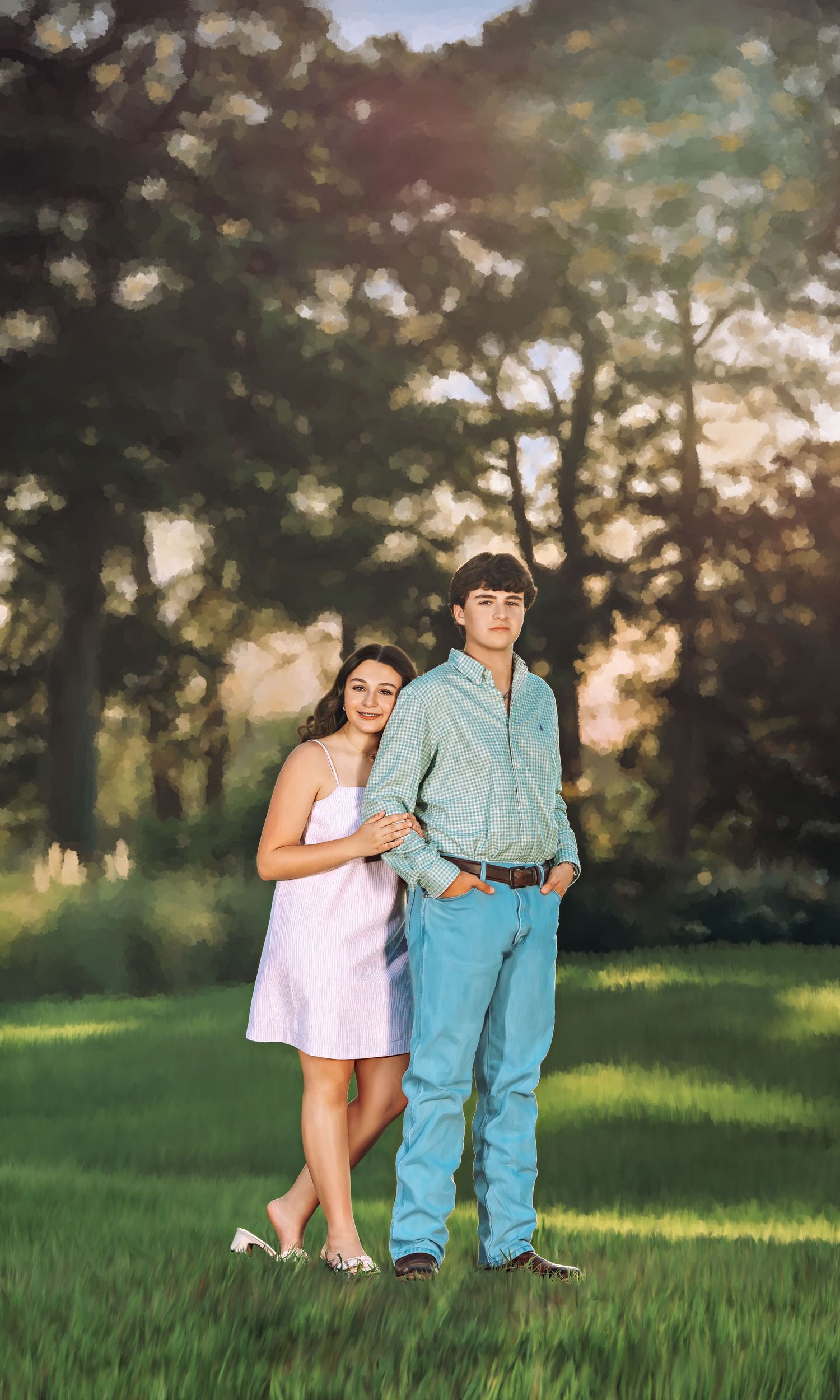 A young couple poses together in a sunlit green field, the girl in a white dress and the boy in a teal shirt and jeans.