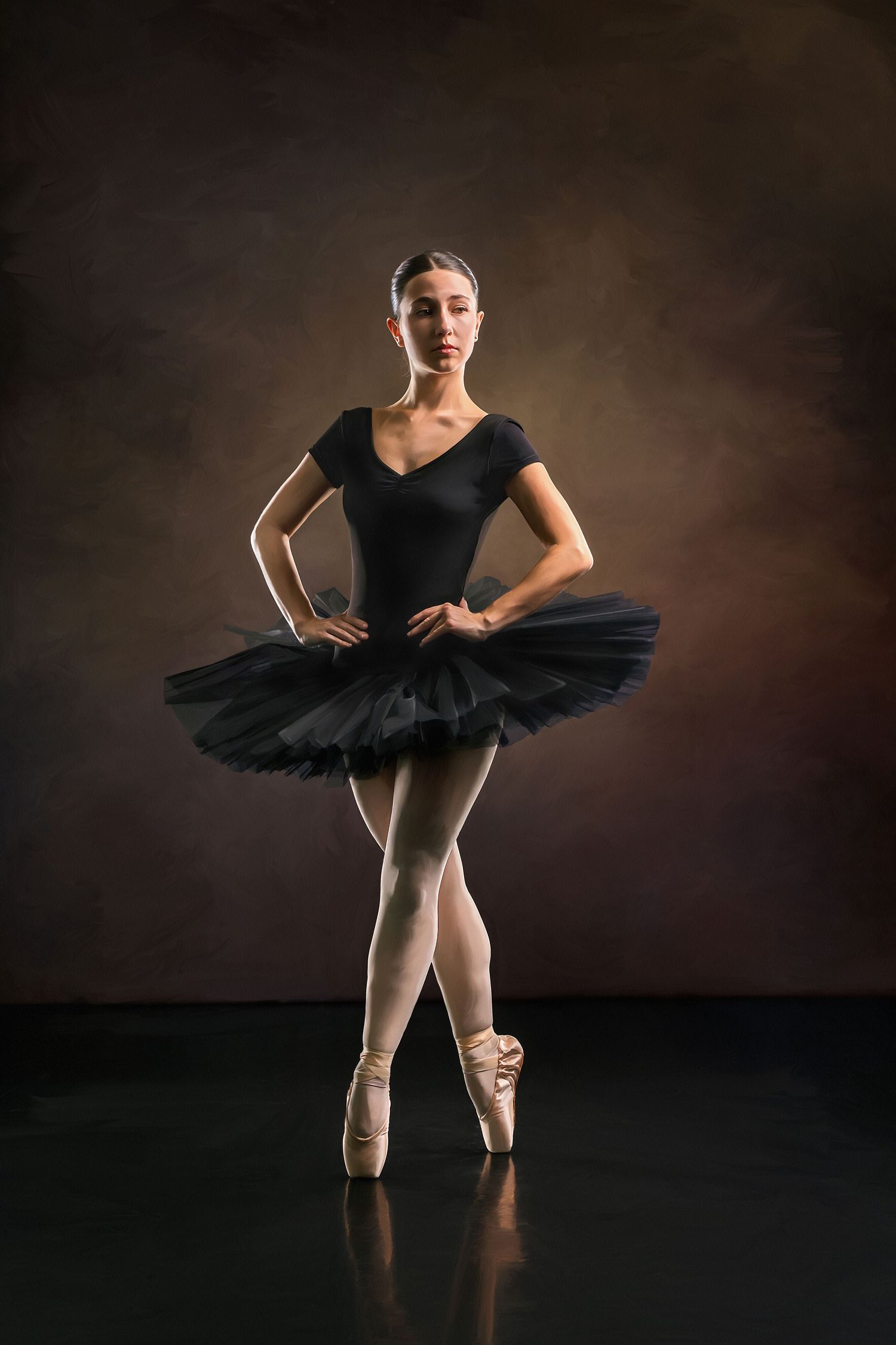 Elegant ballerina in black tutu and pointe shoes poses gracefully against a dark studio backdrop.