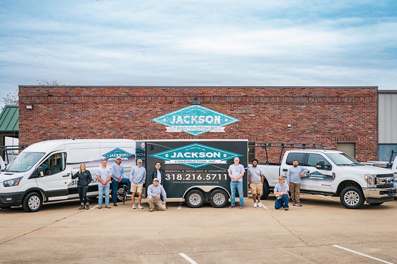 Jackson team members gather with service vans and trailer outside company headquarters.