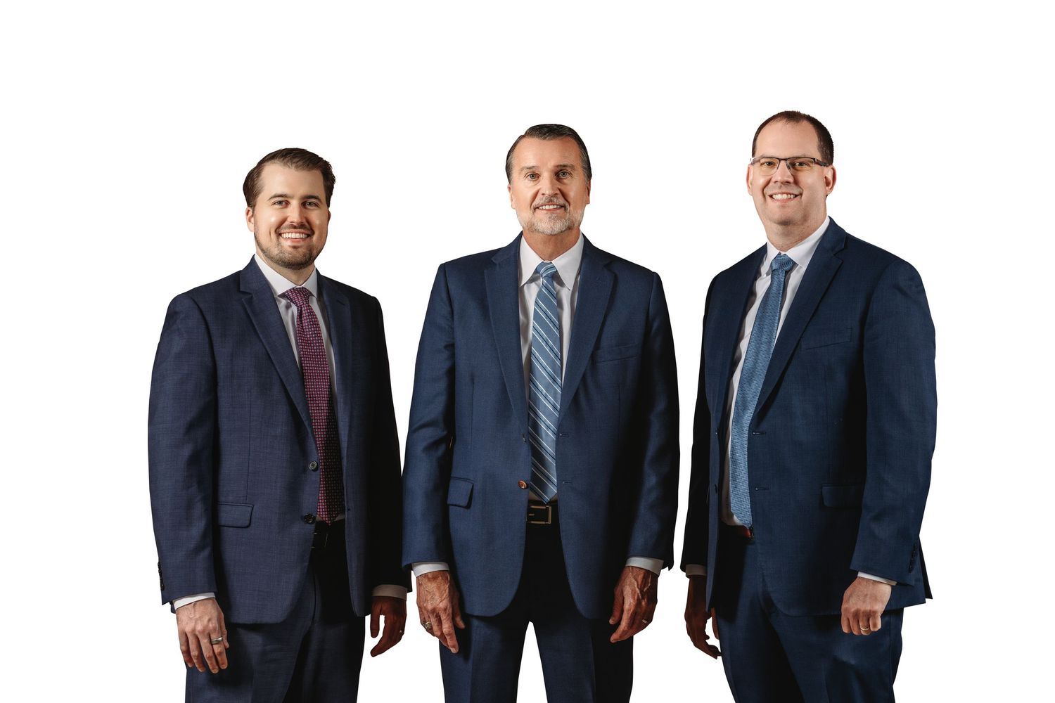 Three professional businessmen in navy suits smiling together against a white background.