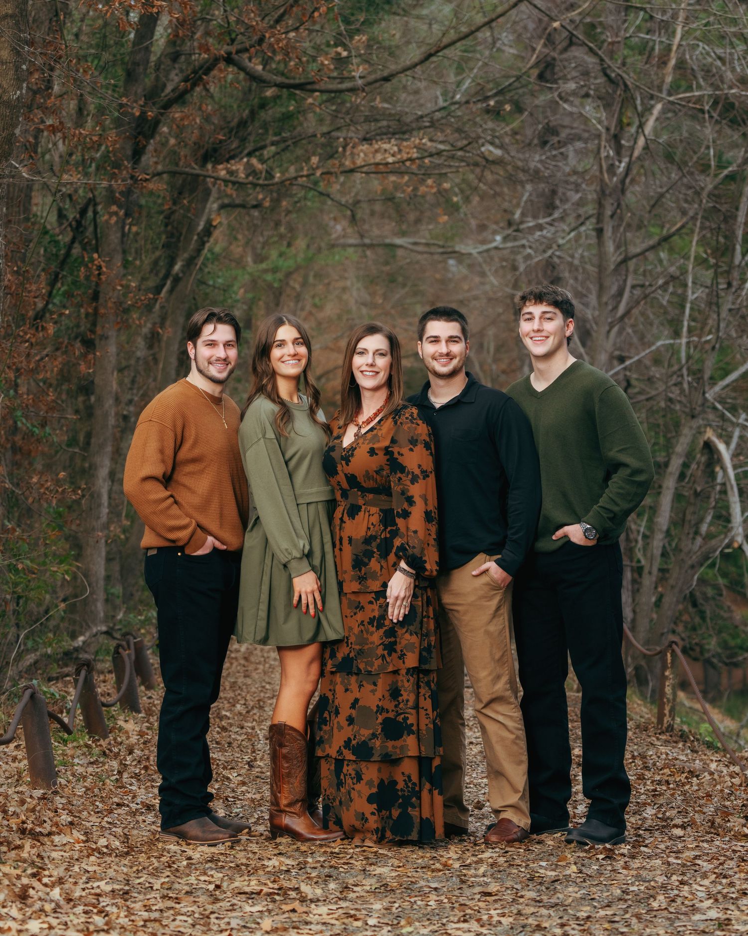 A family of five poses on a scenic autumn forest path with fall foliage backdrop.