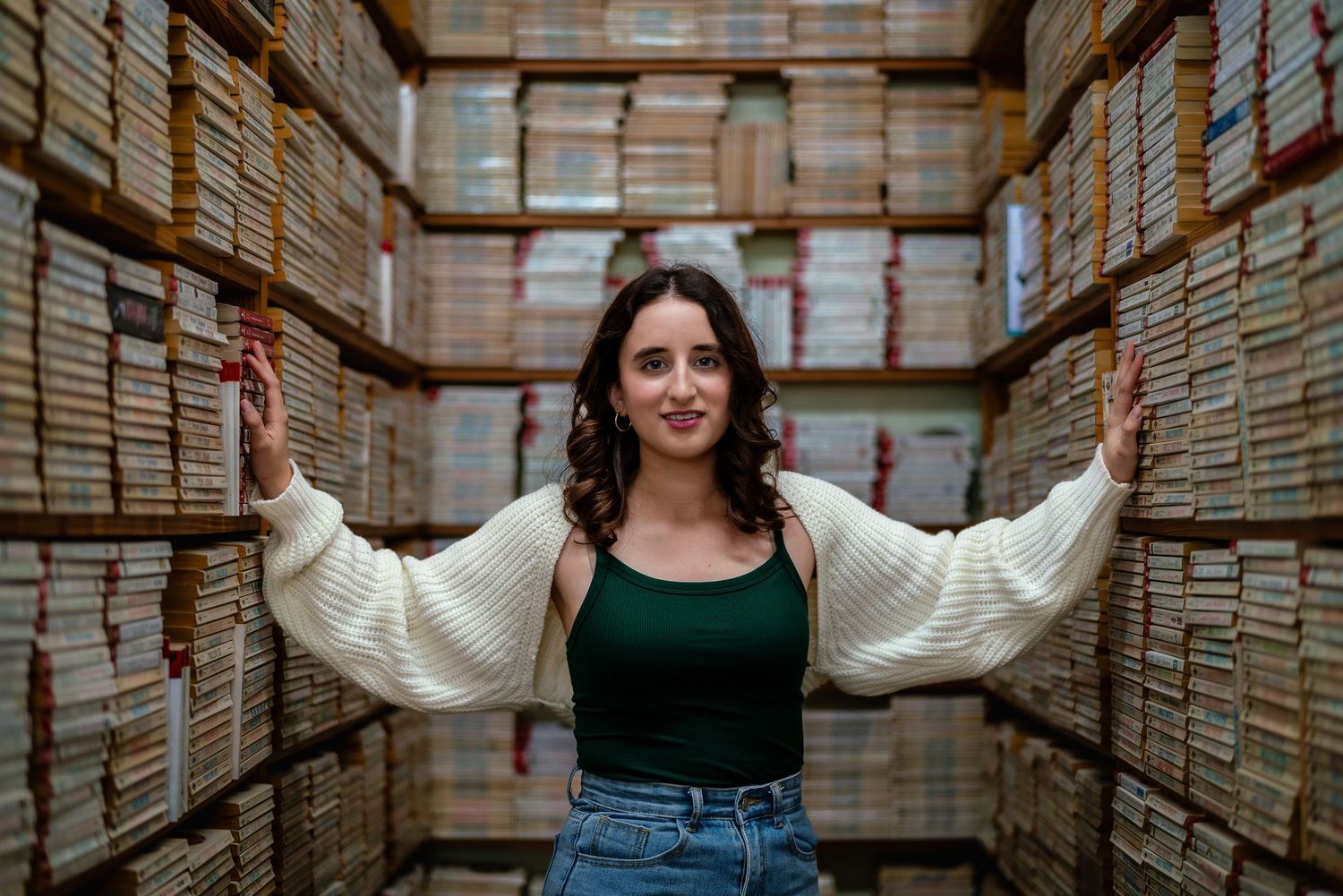 Young woman stands confidently between tall archive shelves filled with records and files.