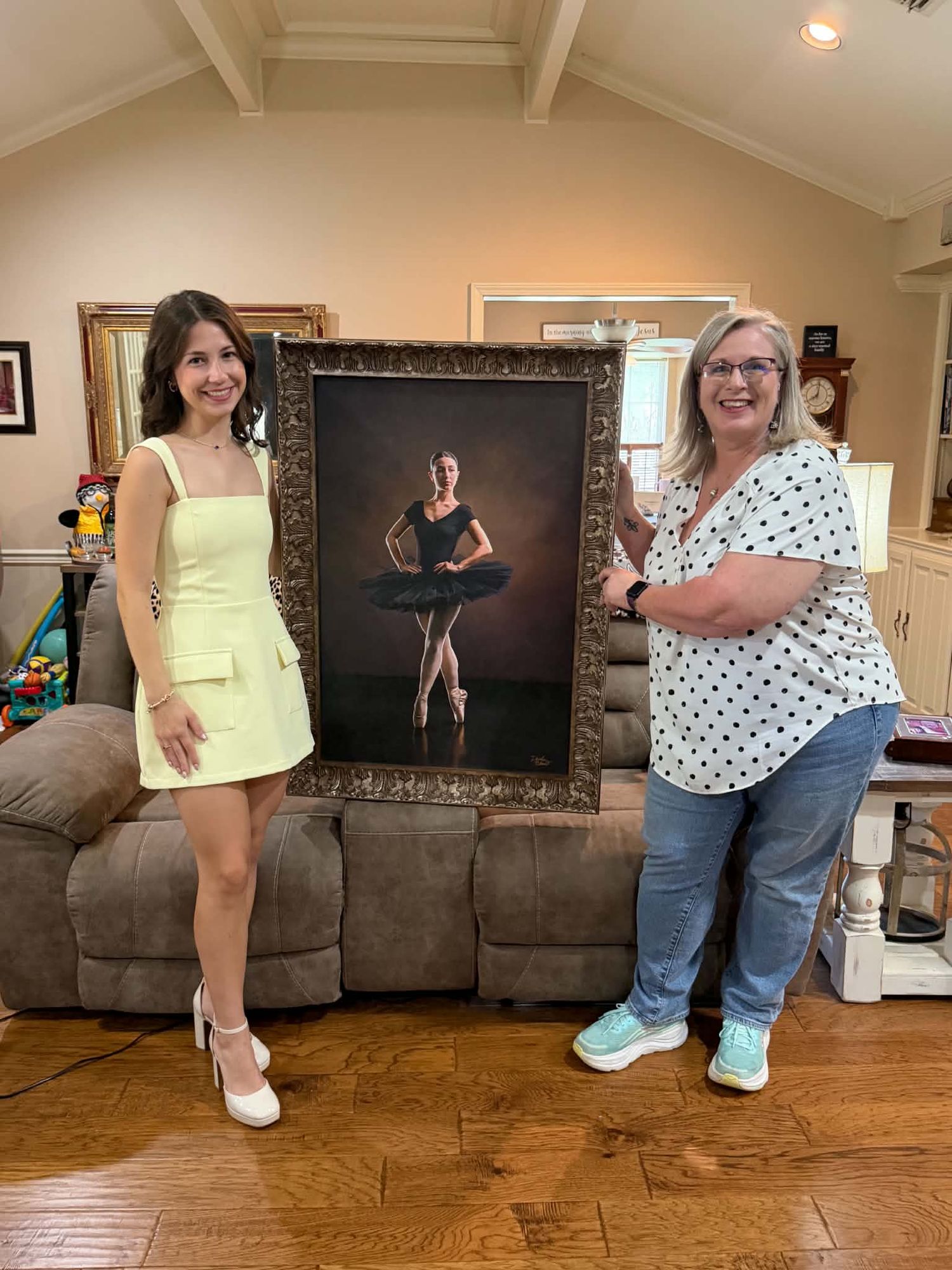 Young woman and photographer proudly displaying a large framed ballet dancer portrait indoors.