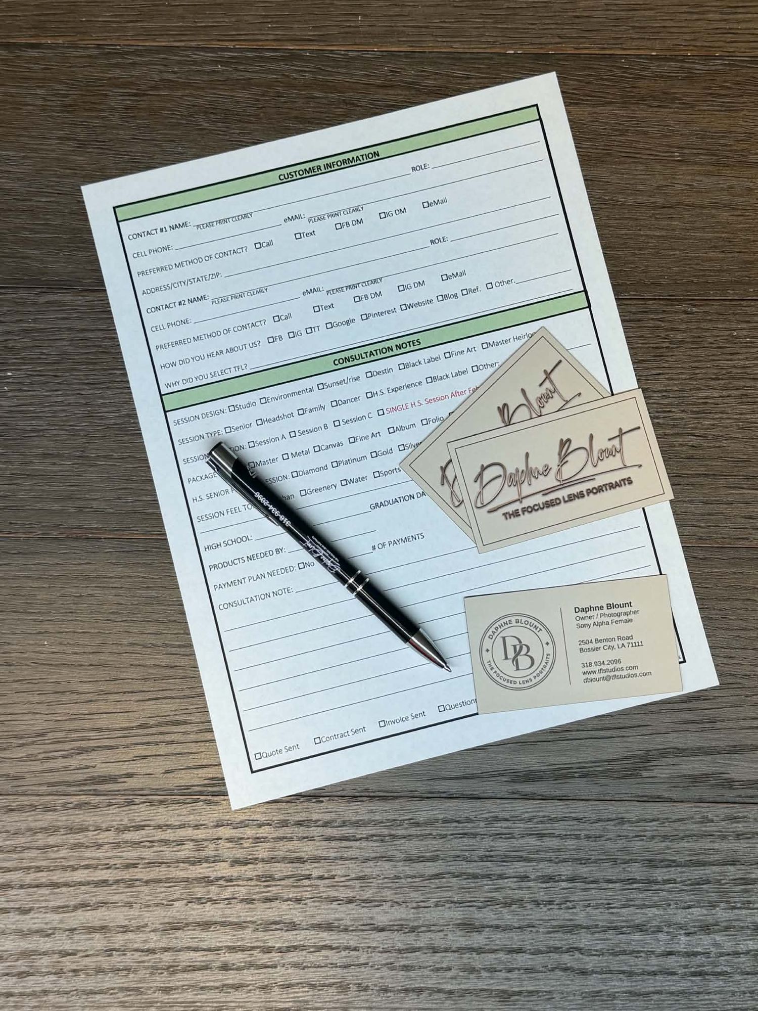 Daphne BlOunt portrait photography client information form with business cards and pen on wood.