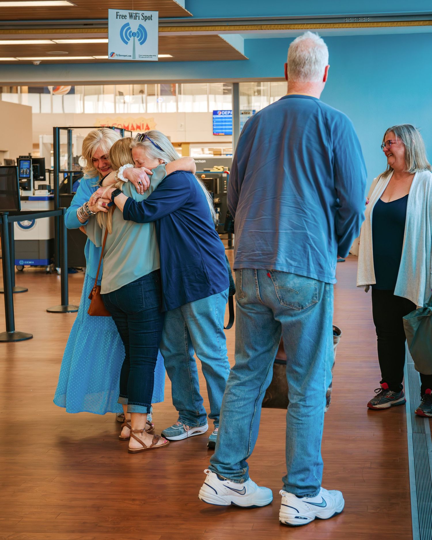 Emotional reunion with people embracing warmly inside an airport terminal.