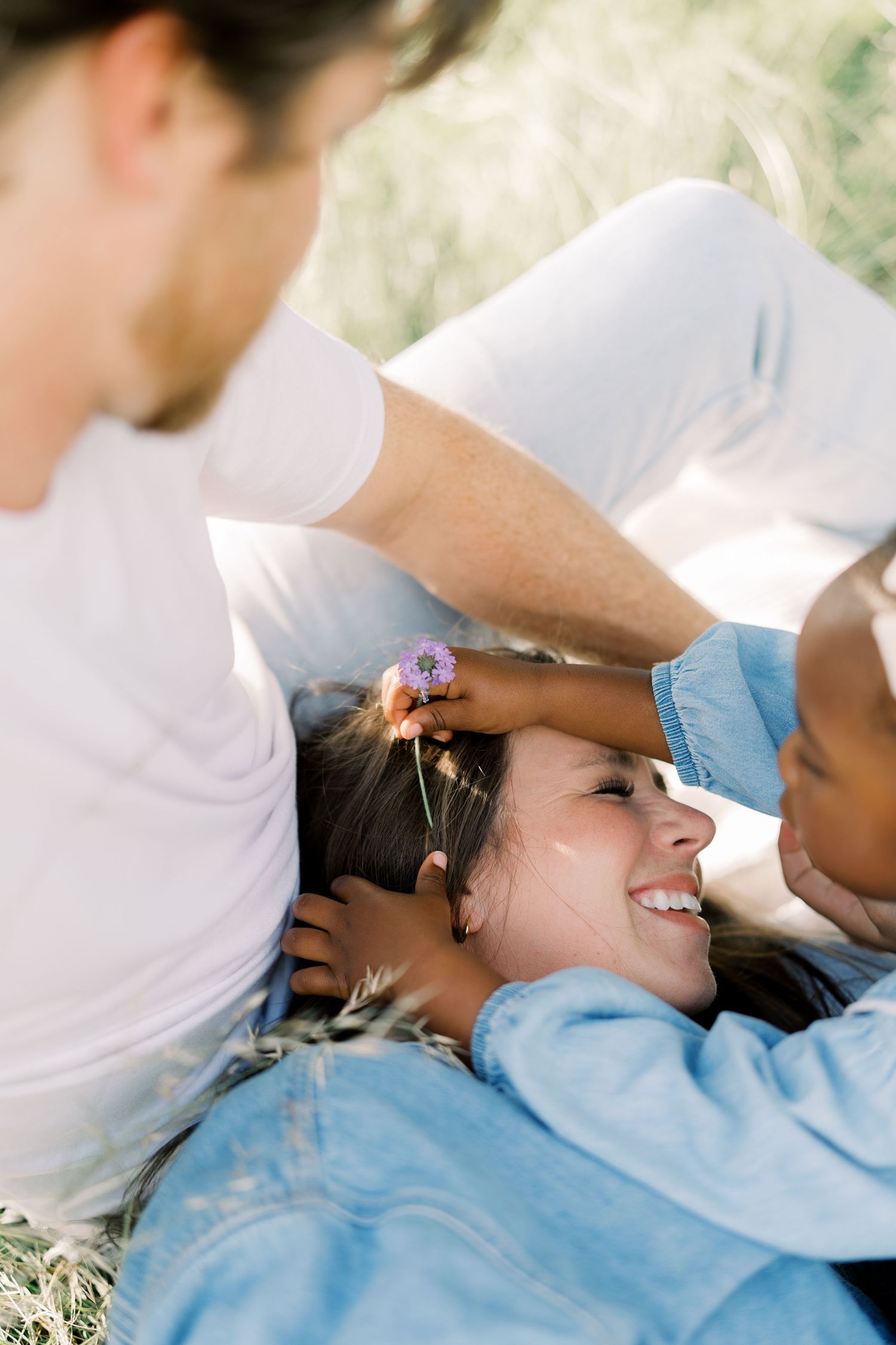A man places a small purple flower in a smiling woman's hair outdoors in Dallas by Alahir Villasenor Photography.