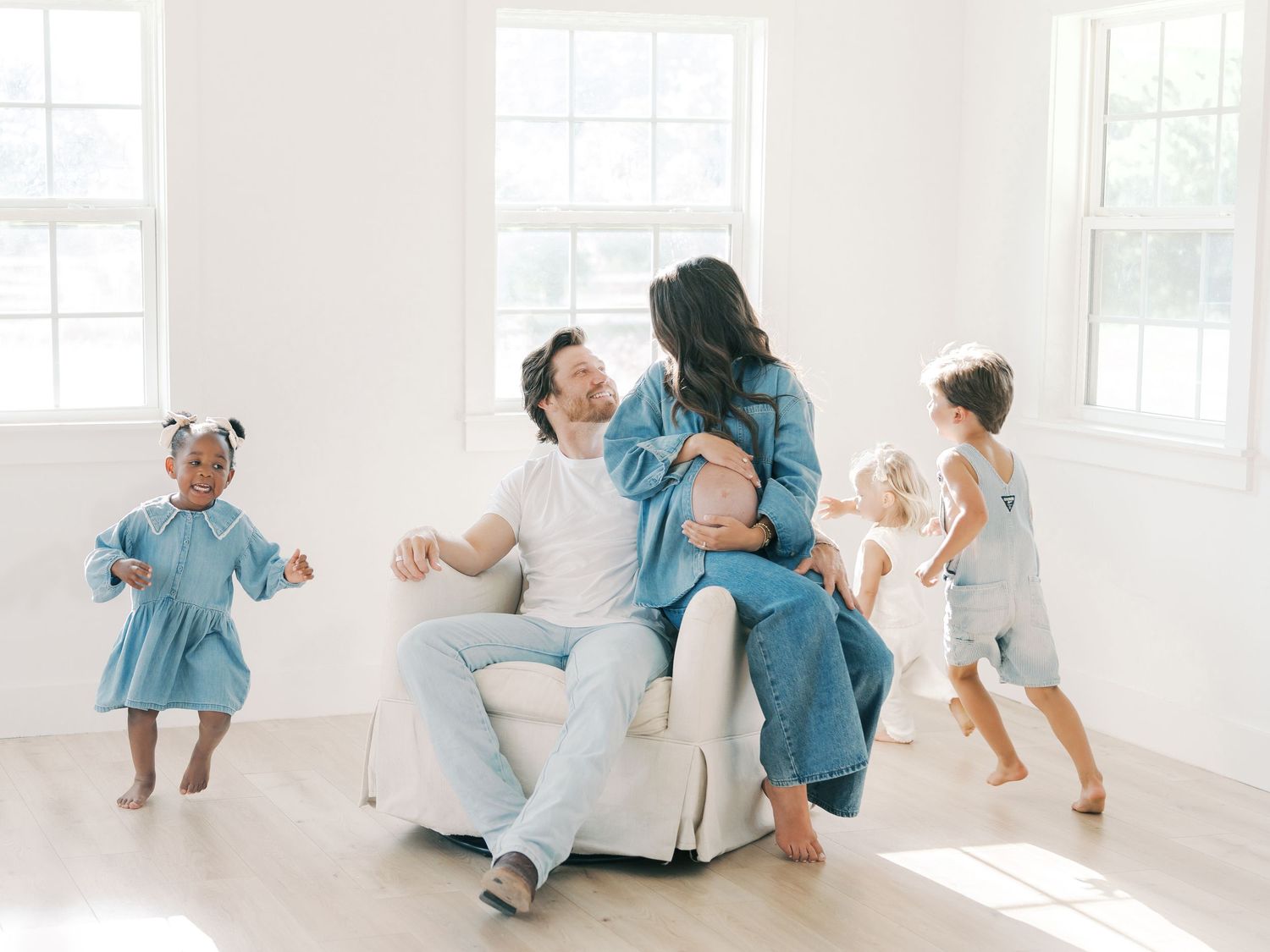 Happy family with three children enjoys a bright white studio session with pregnant mother by Alahir Villasenor Photographer