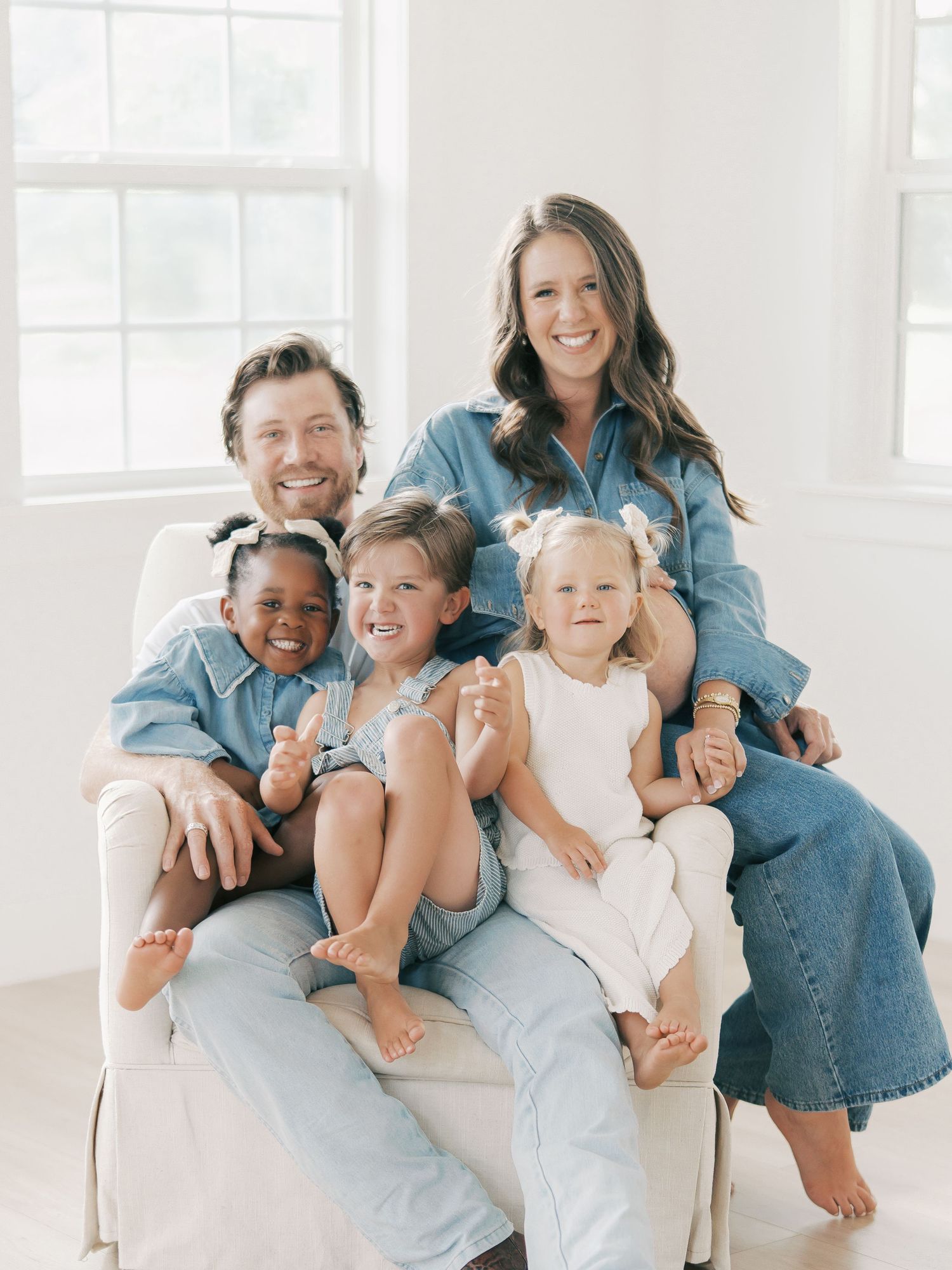 Happy family of five in denim outfits poses together in a bright white studio in Dallas by Alahir Villasenor Photography-Family Session