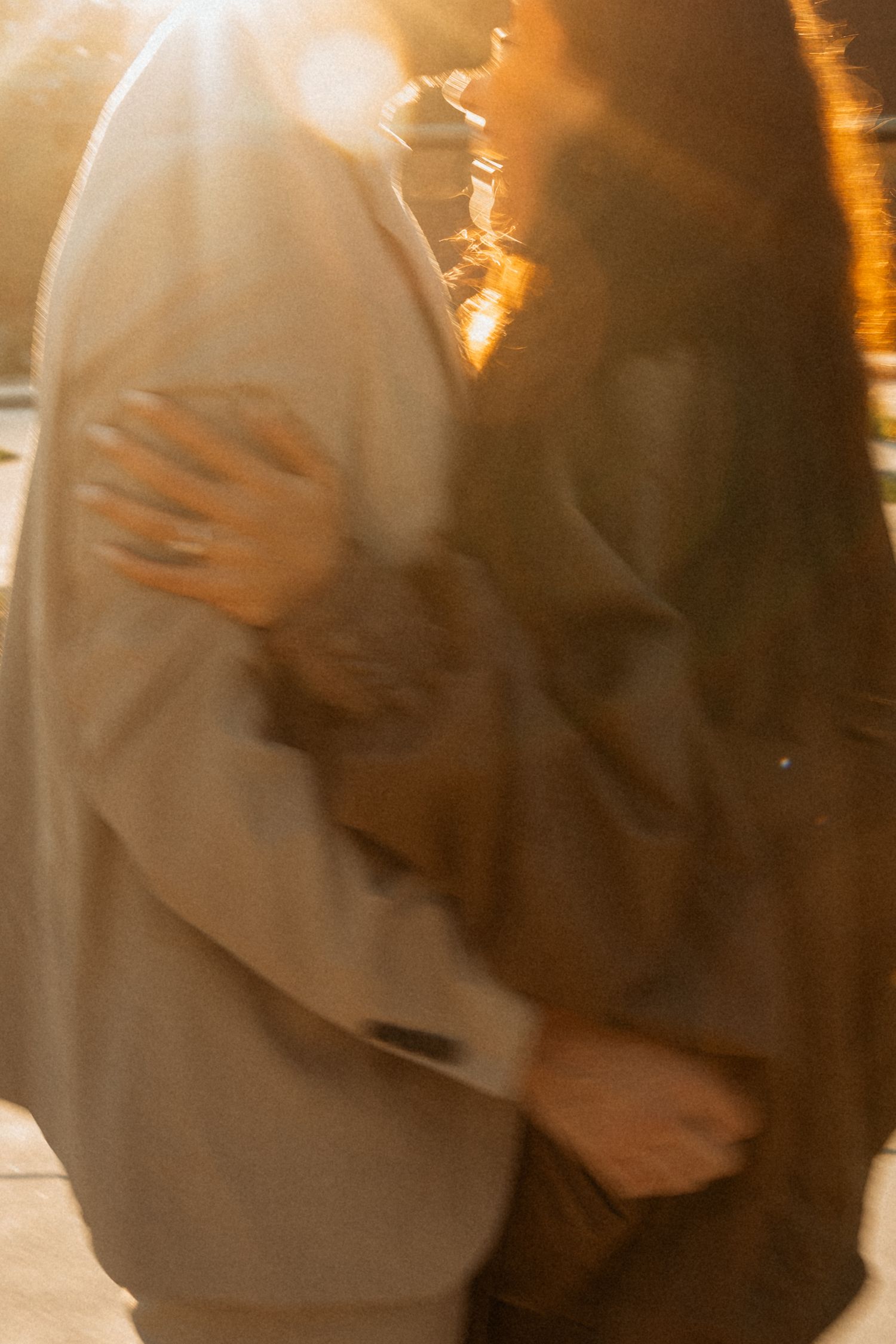 Couple embracing in warm golden sunset light, sharing a romantic moment outdoors.