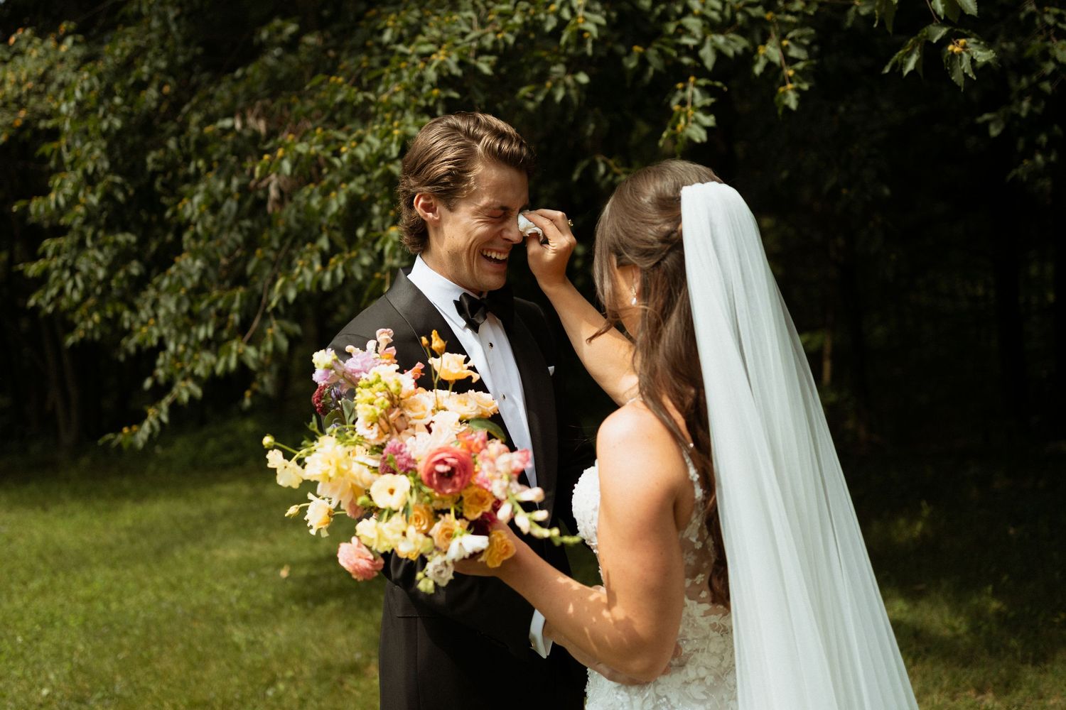 Groom smiling at bride during outdoor first look with colorful bridal bouquet.