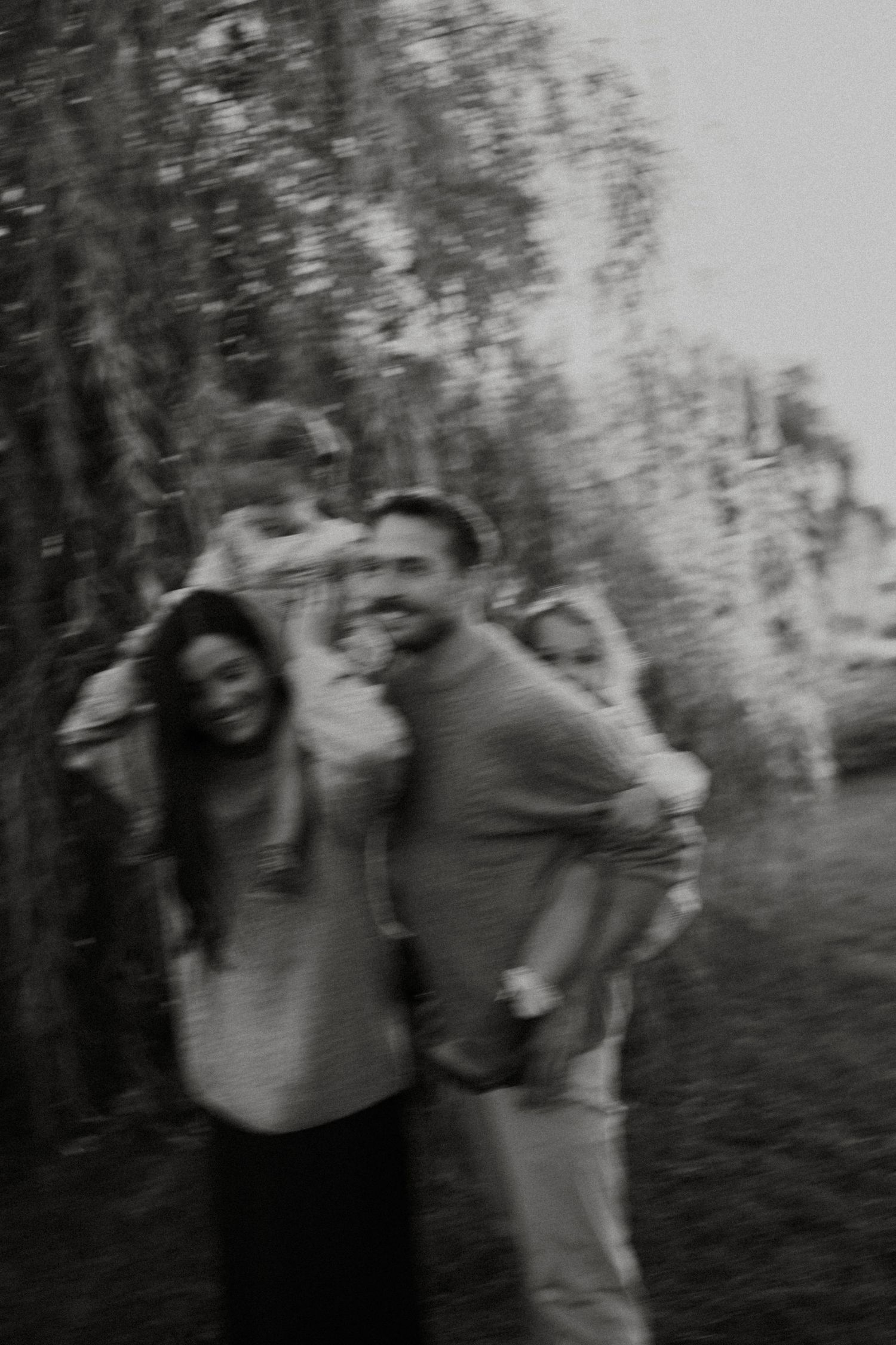 Black and white blurred photo of a happy family with two children outdoors among trees.