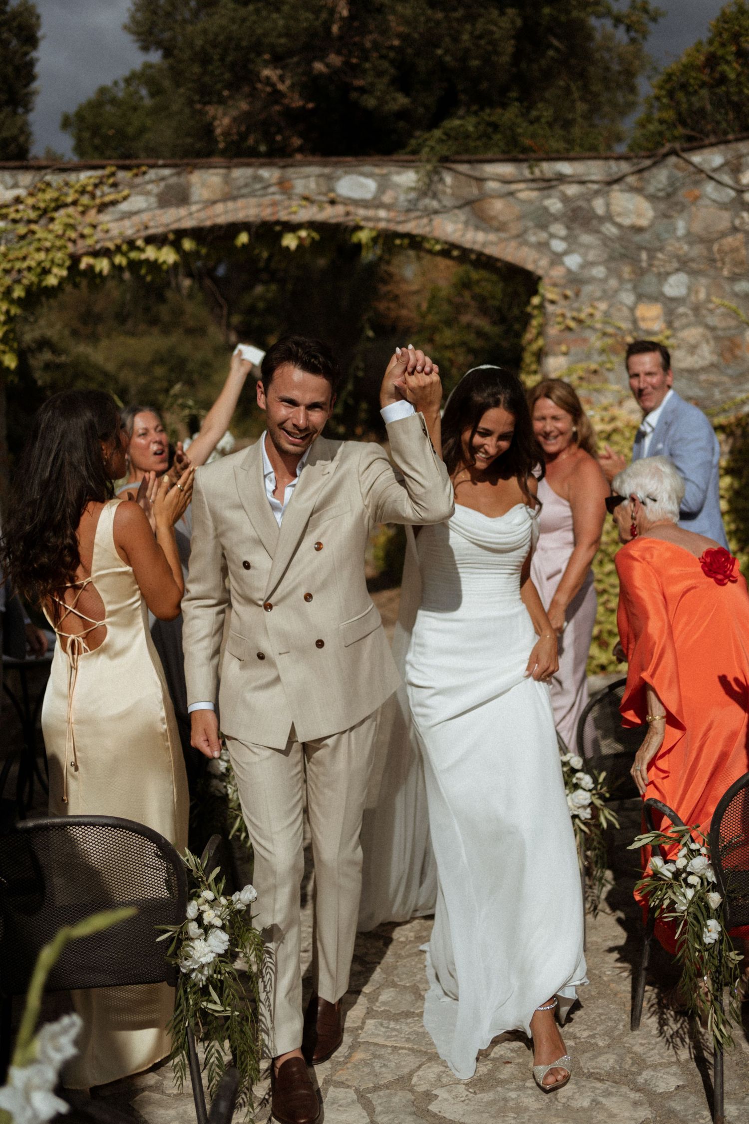 A joyful bride and groom raise their hands as they walk back down the aisle after their ceremony.