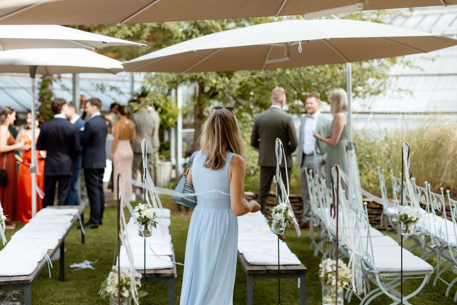 Wedding guests mingling on lawn with white ceremony chairs.