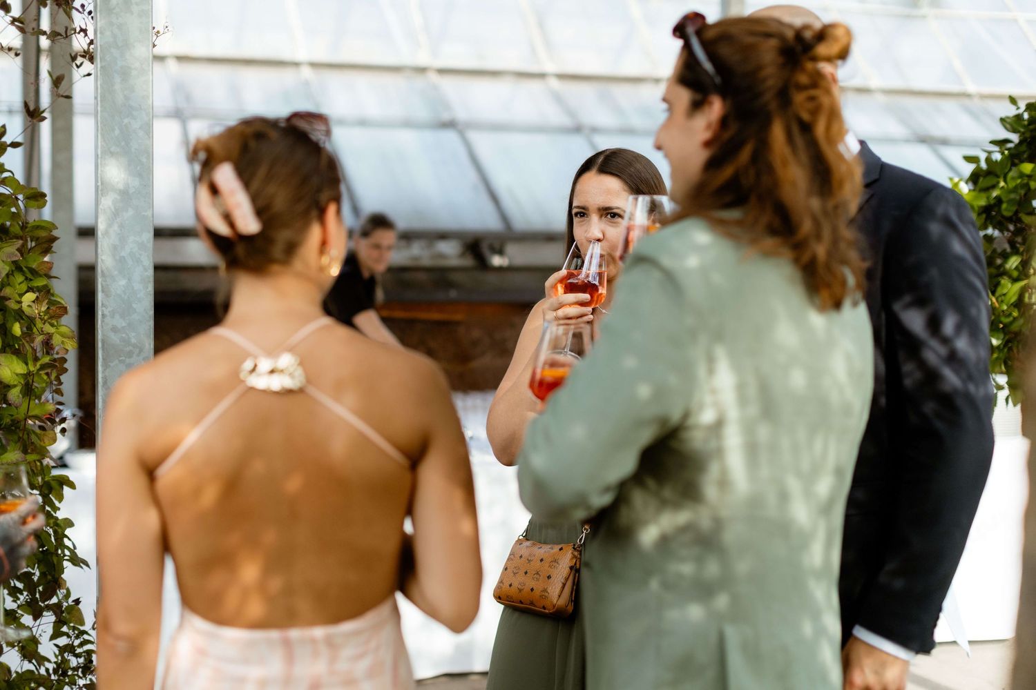 Wedding guests socializing and drinking cocktails at outdoor reception.