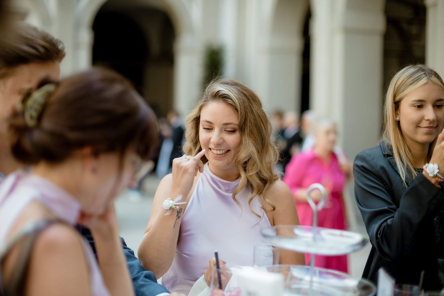 Smiling woman in lavender dress enjoying food at an elegant wedding reception outdoor event.