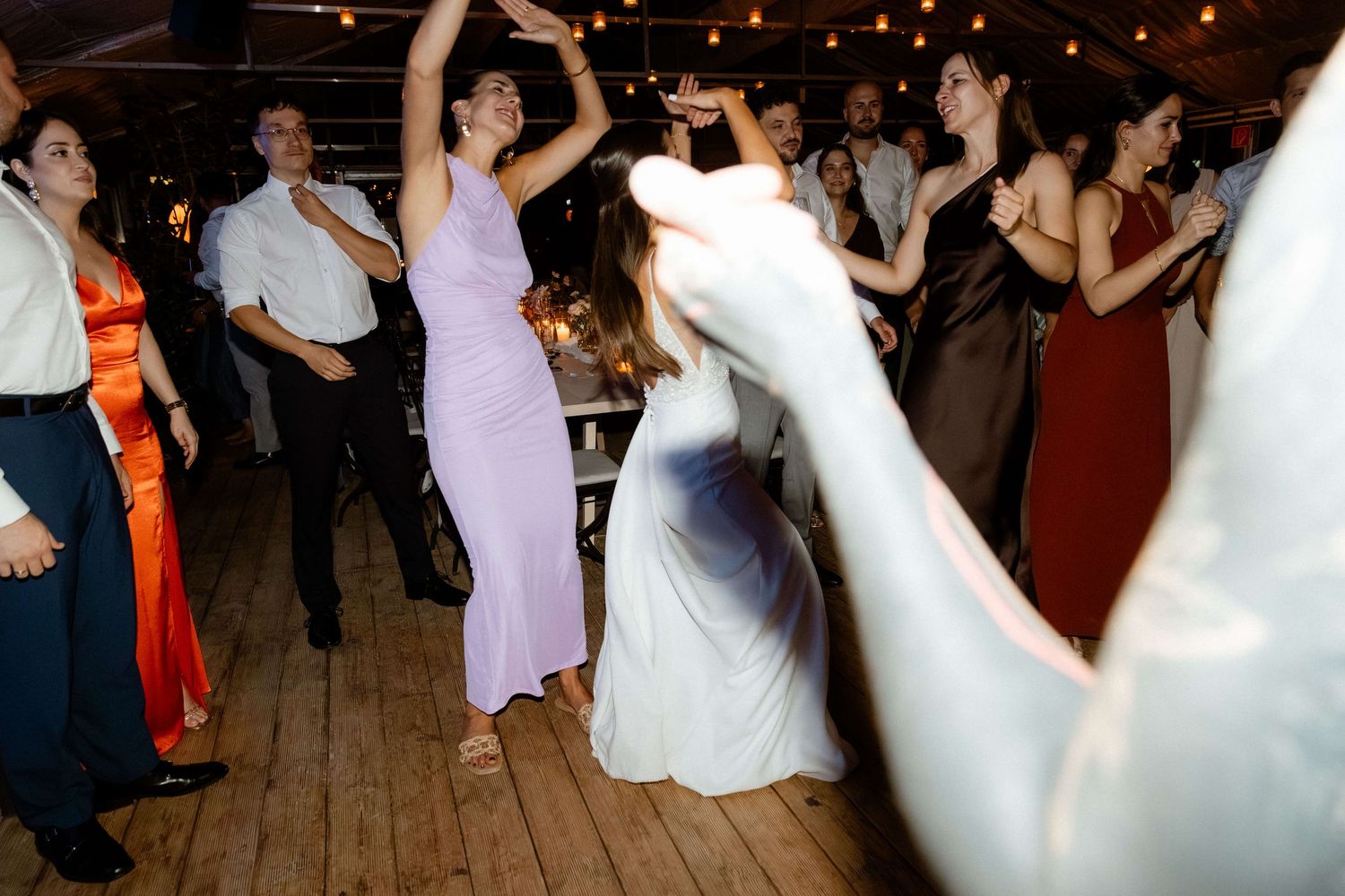 Energetic wedding reception dance floor with guests in colorful formal attire celebrating.