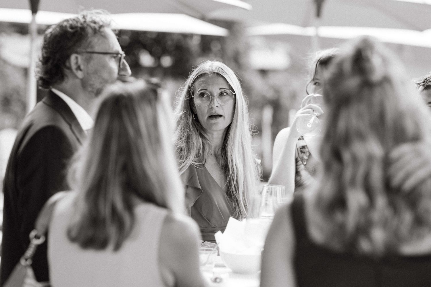 Black and white photo of blonde woman with surprised expression at wedding reception.