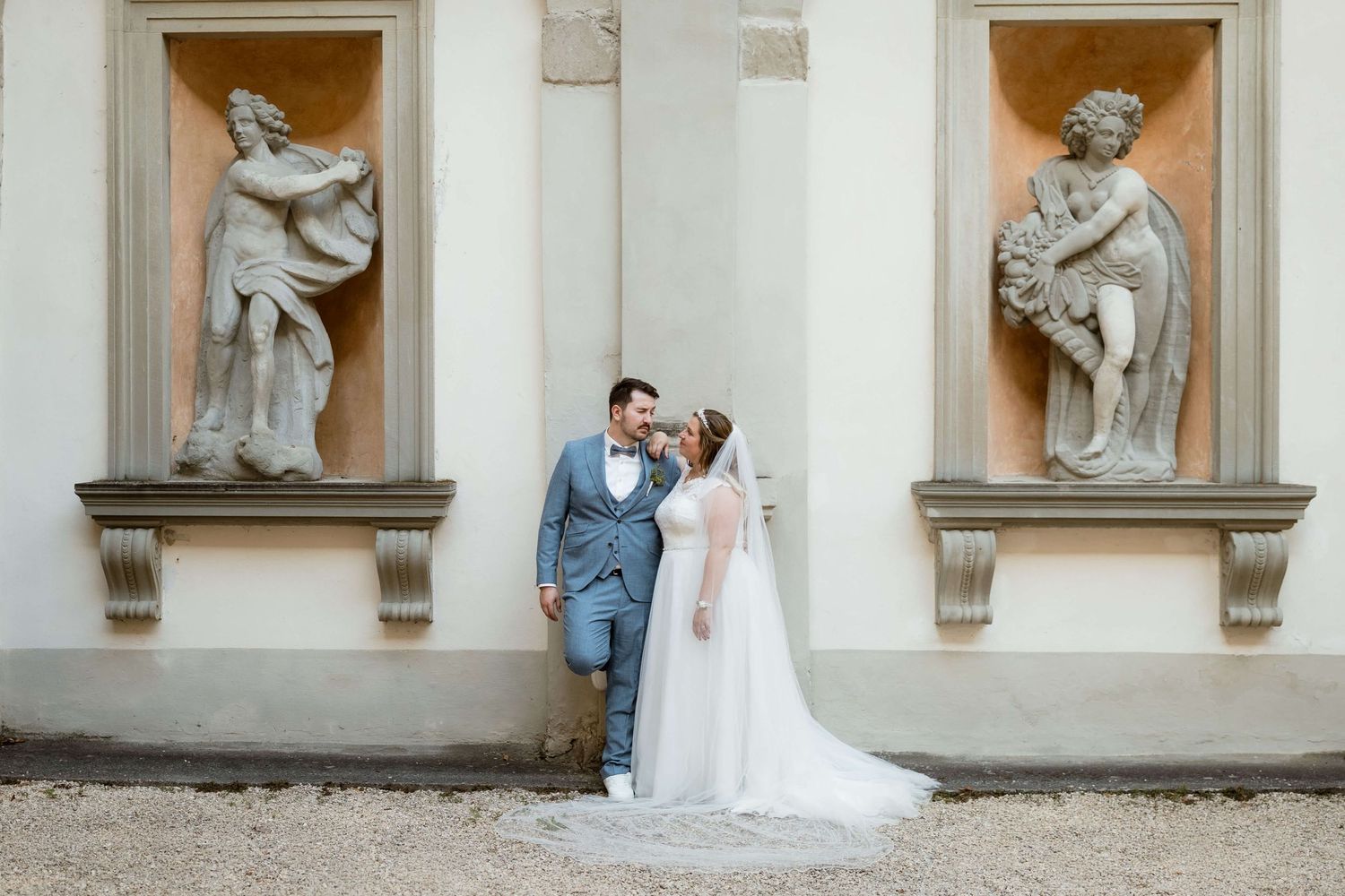 Bride and groom sharing a romantic kiss in front of ornate wall sculptures at wedding venue.