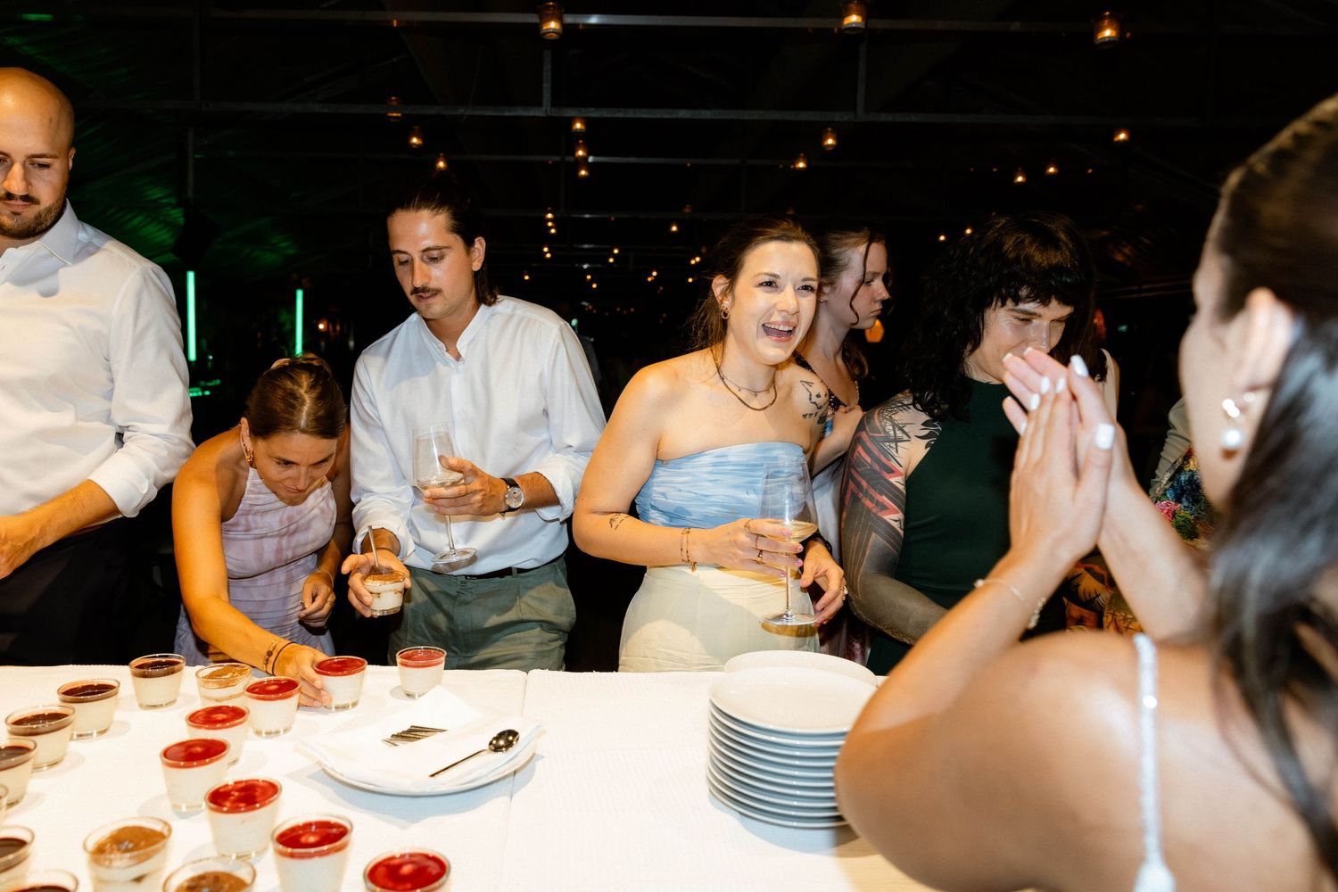 Wedding guests enjoying desserts and celebrating at reception table with small dishes.