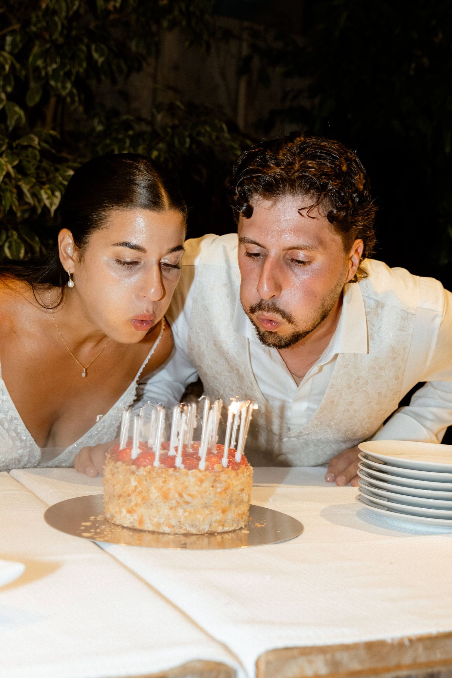 Bride and groom blowing out candles on their wedding cake together.