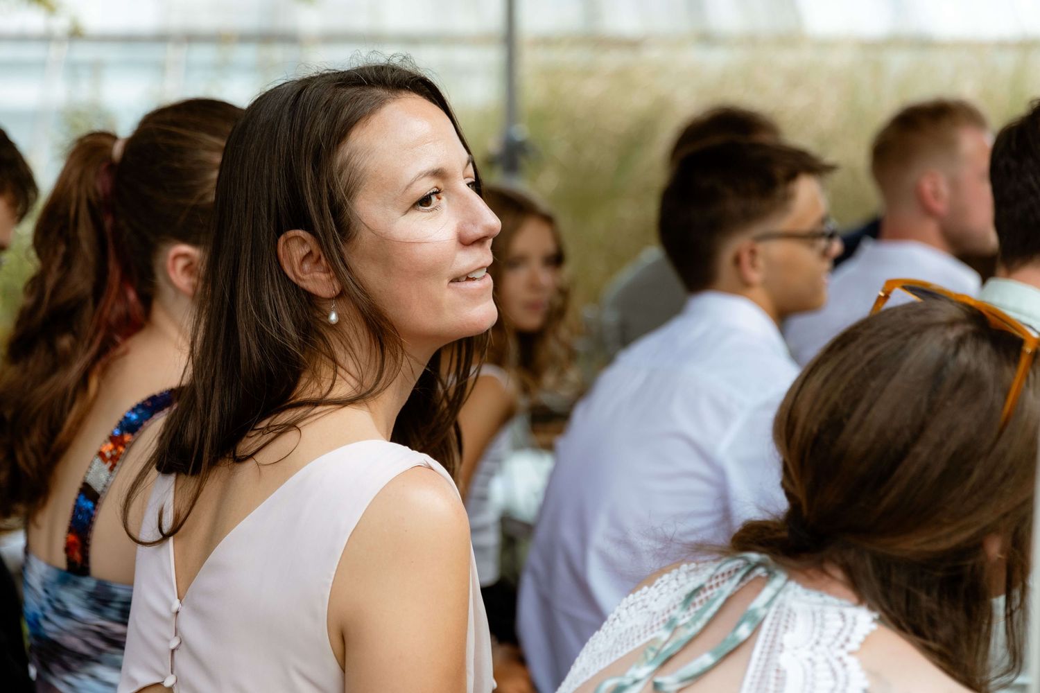 Woman with brown hair gazing upward at outdoor wedding reception.