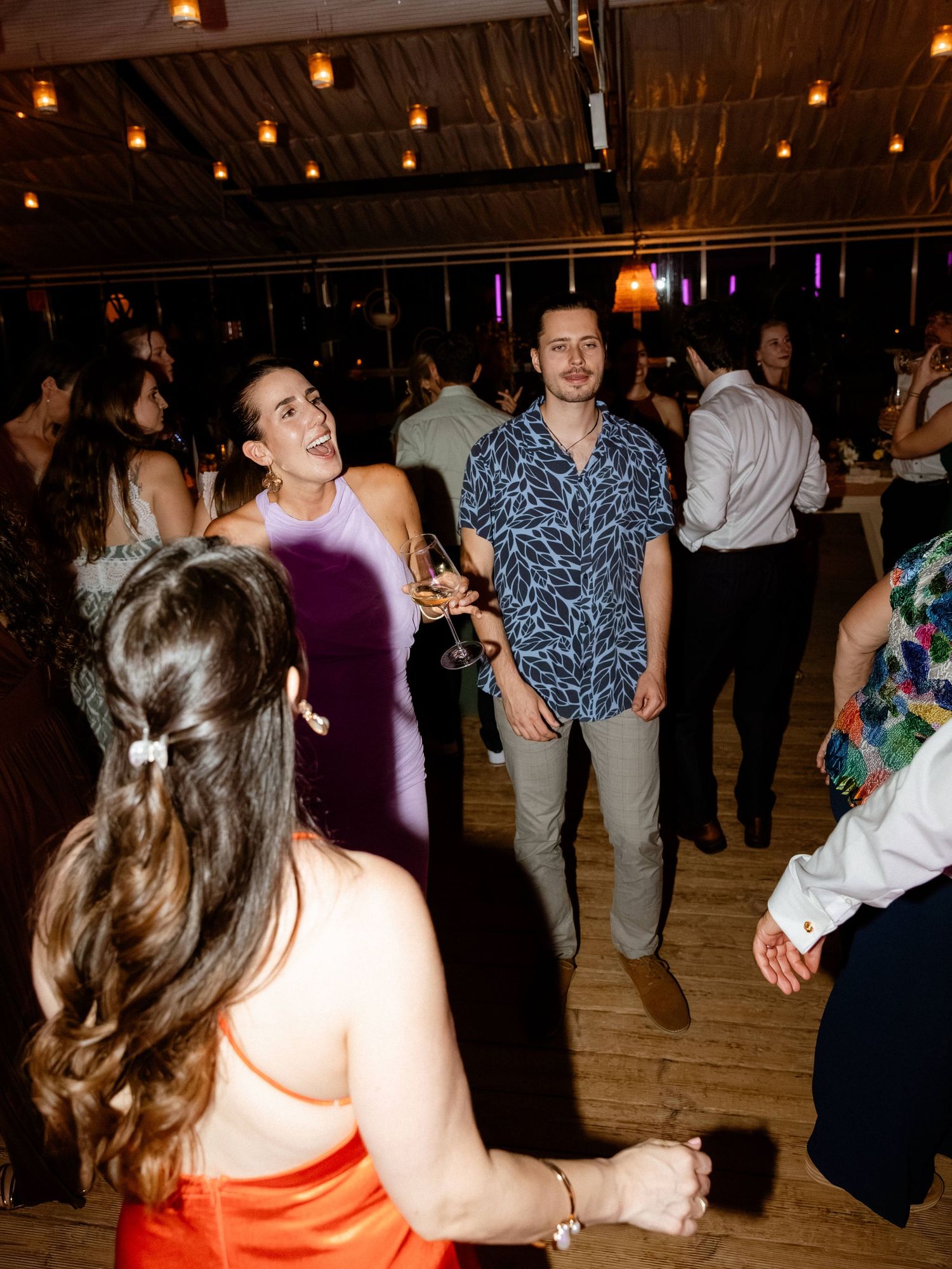 Guests smiling and dancing at an elegant indoor wedding reception celebration.