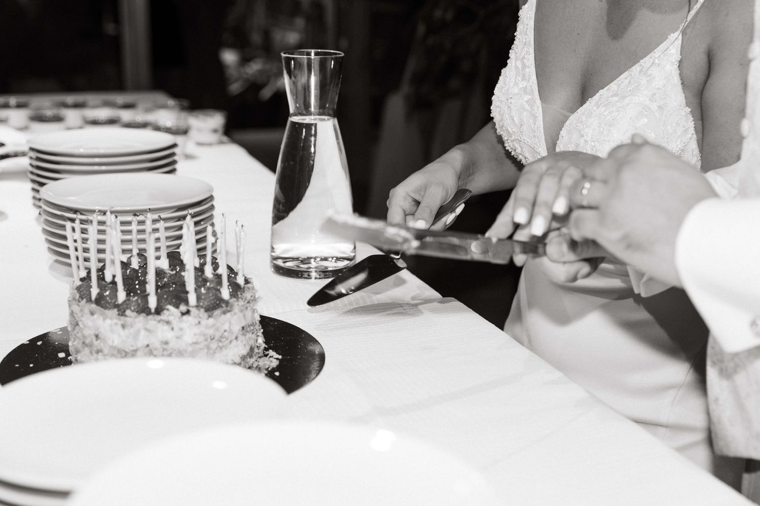 Bride and groom cutting their wedding cake in a black and white photo.