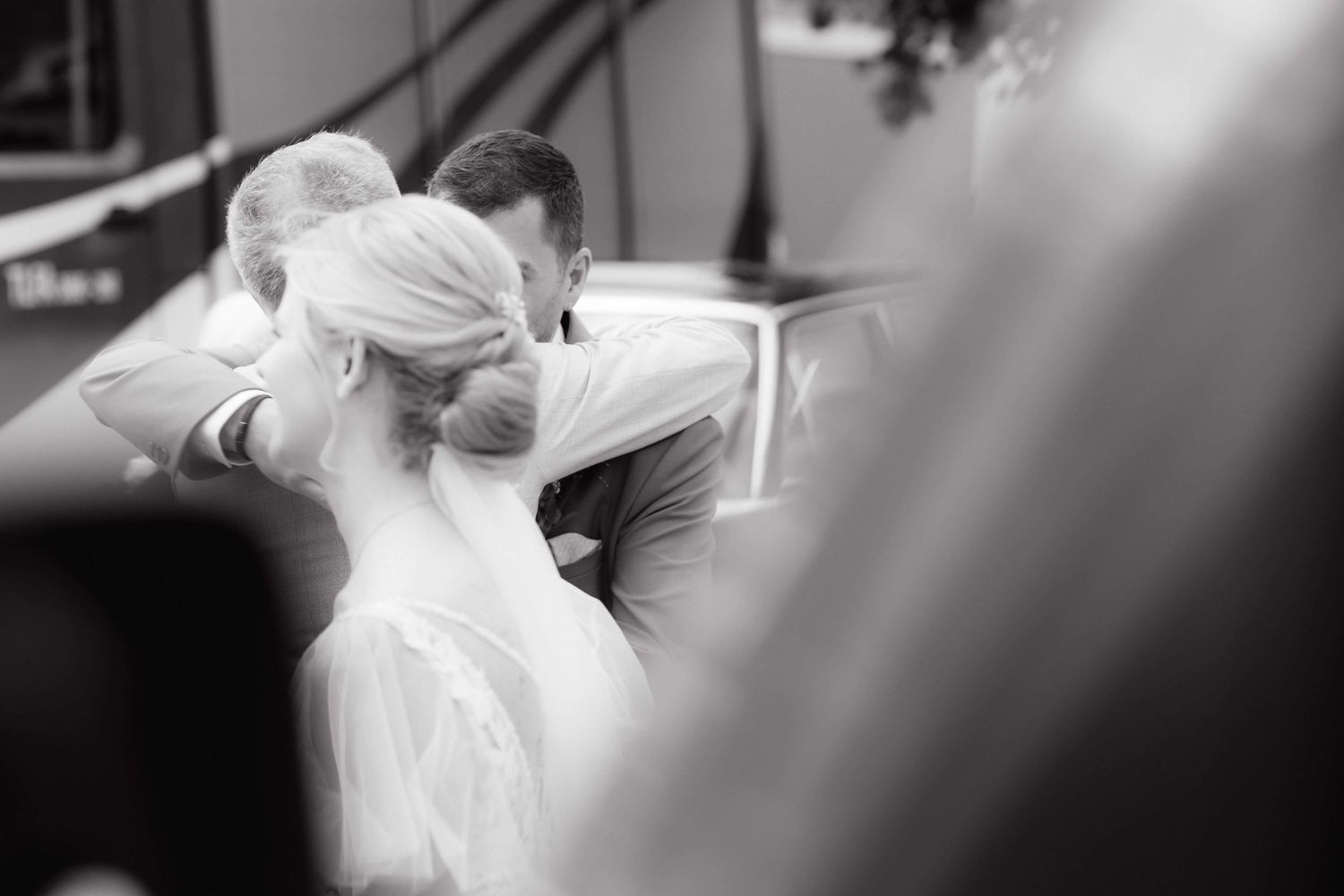 Black and white photo of bride and groom sharing intimate kiss during wedding ceremony.