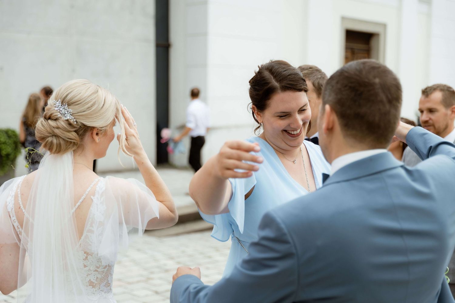 Wedding guests congratulate smiling bride and groom outside a church after ceremony.