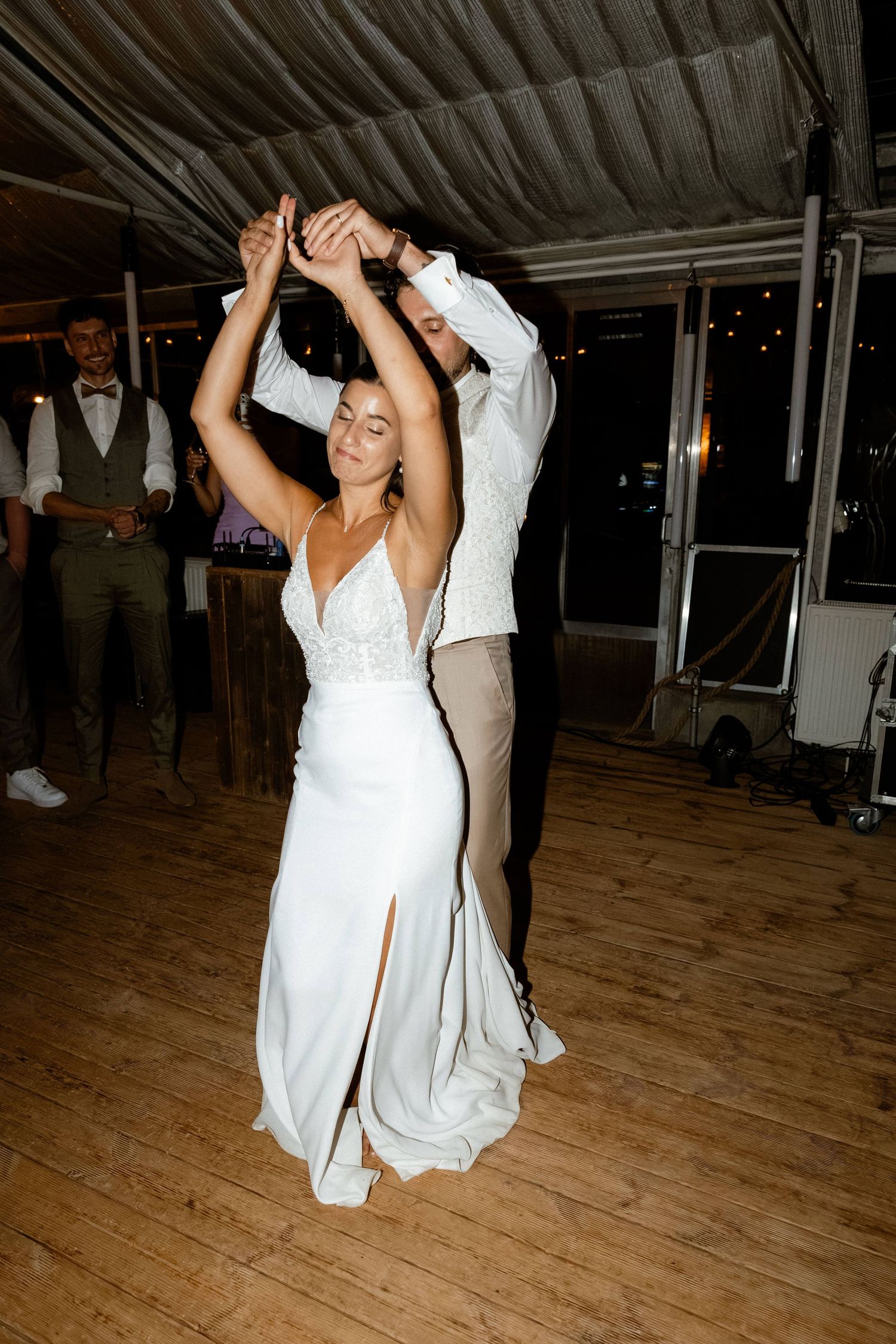 Bride in white gown being twirled by groom during romantic first dance at wedding reception.