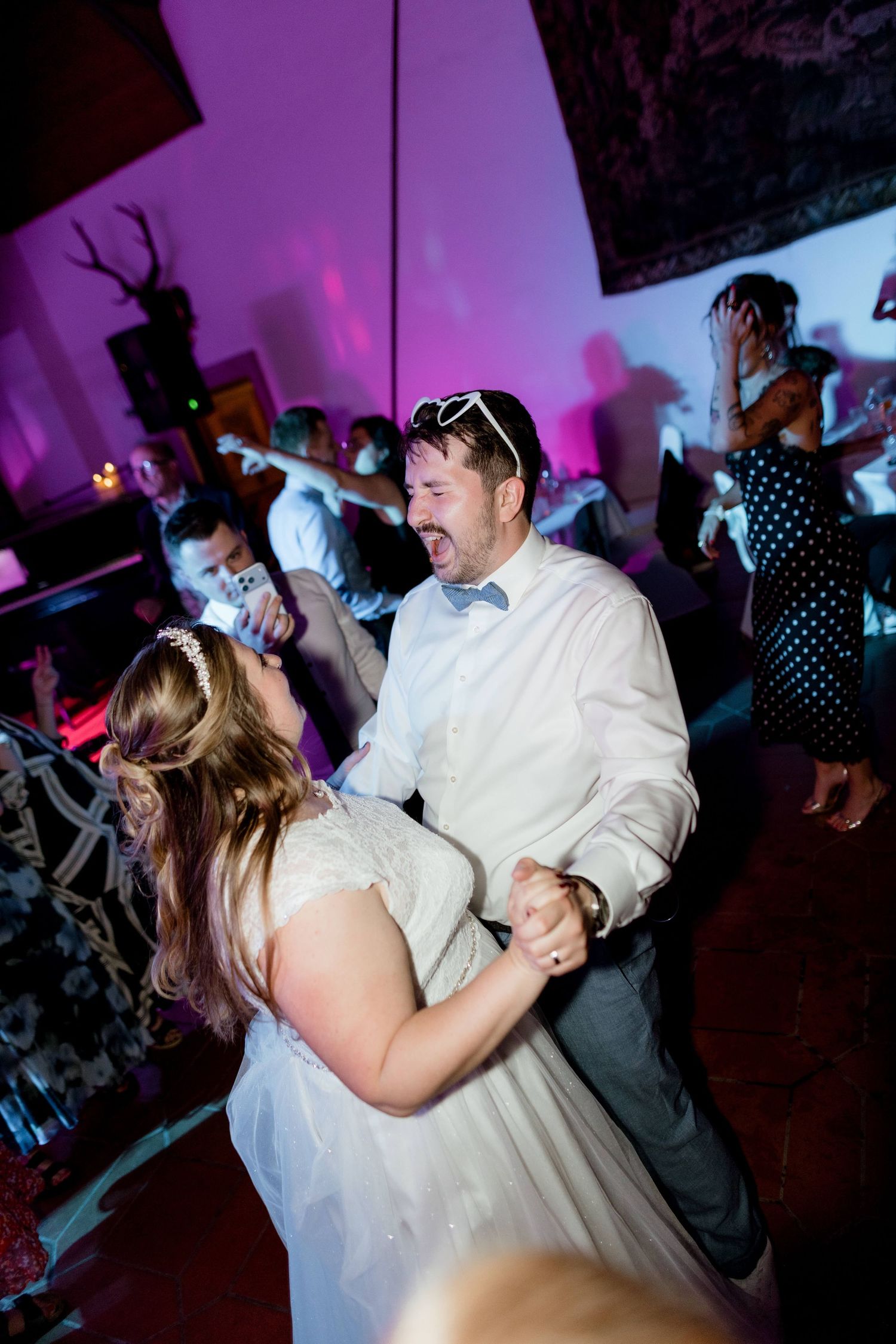 Bride and groom share an energetic dance together under purple lighting at their wedding reception.