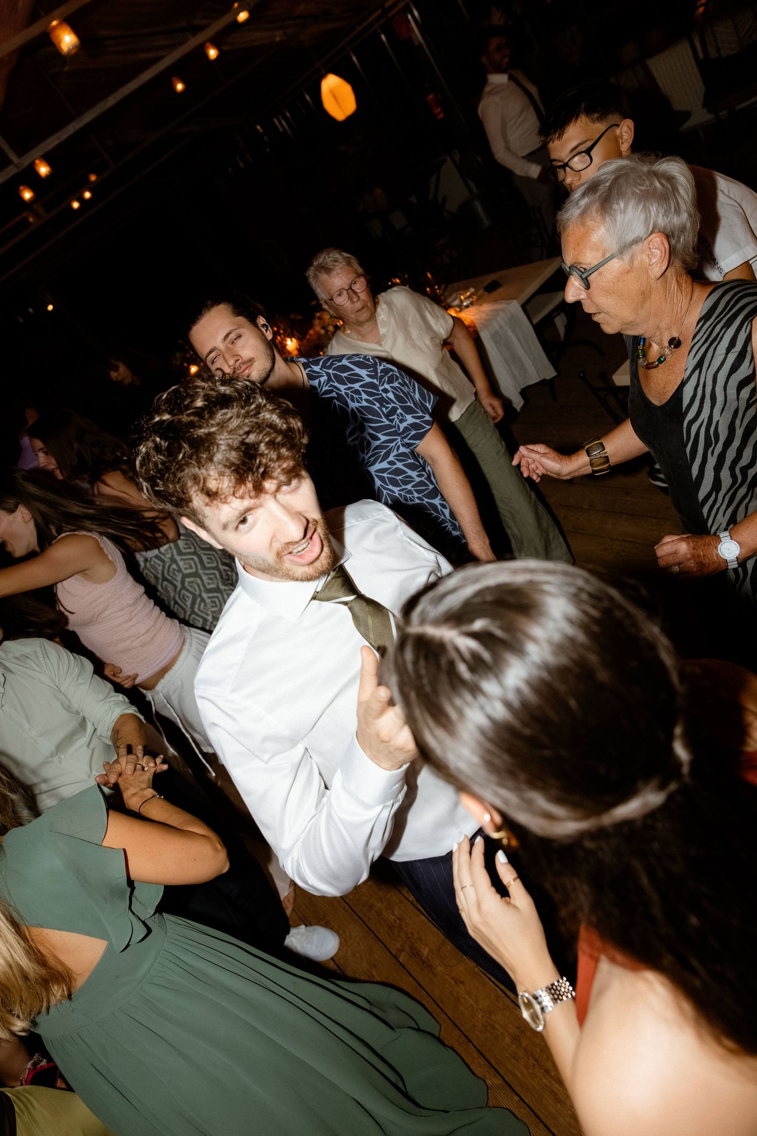 Energetic wedding guest dancing and smiling at a lively wedding reception party.
