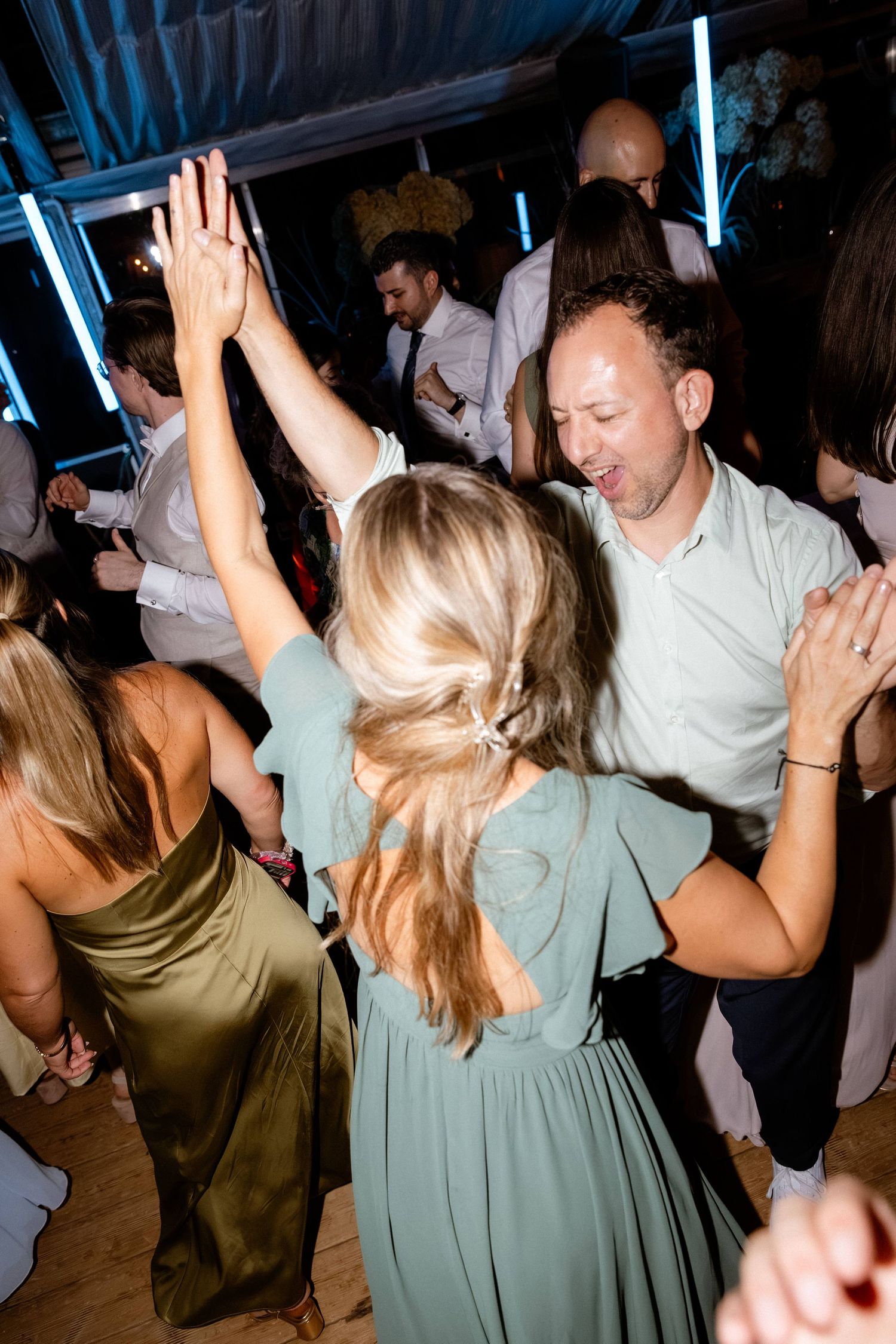 Man and woman in sage green dress dancing together at a wedding reception.