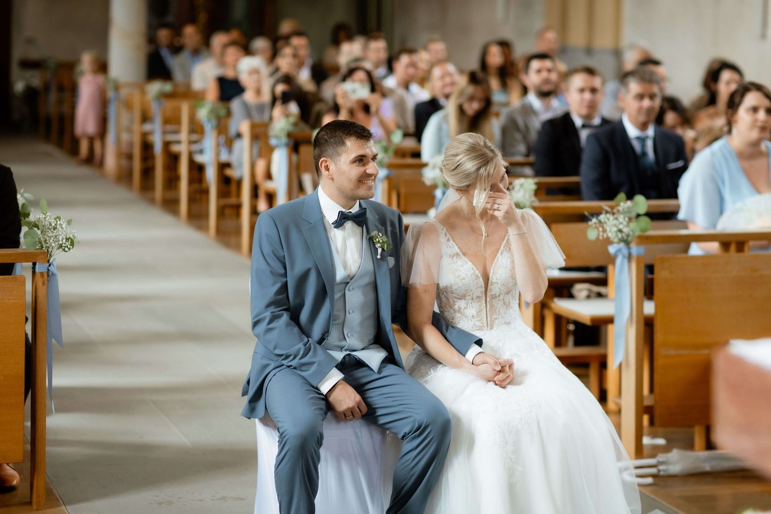 Bride and groom sitting together on church pew during wedding ceremony.