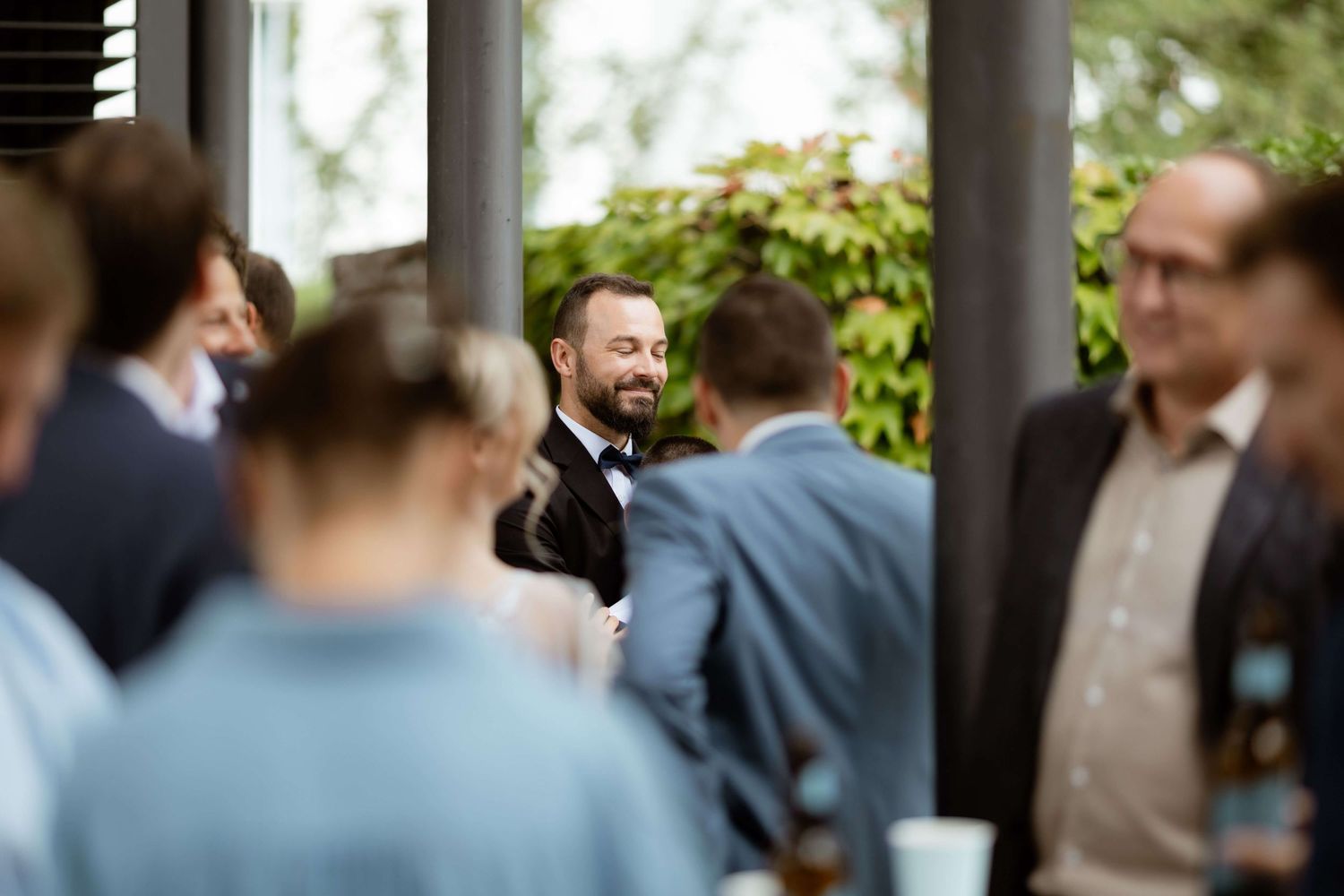 Smiling man with beard in blue suit networking at an outdoor corporate event surrounded by colleagues.