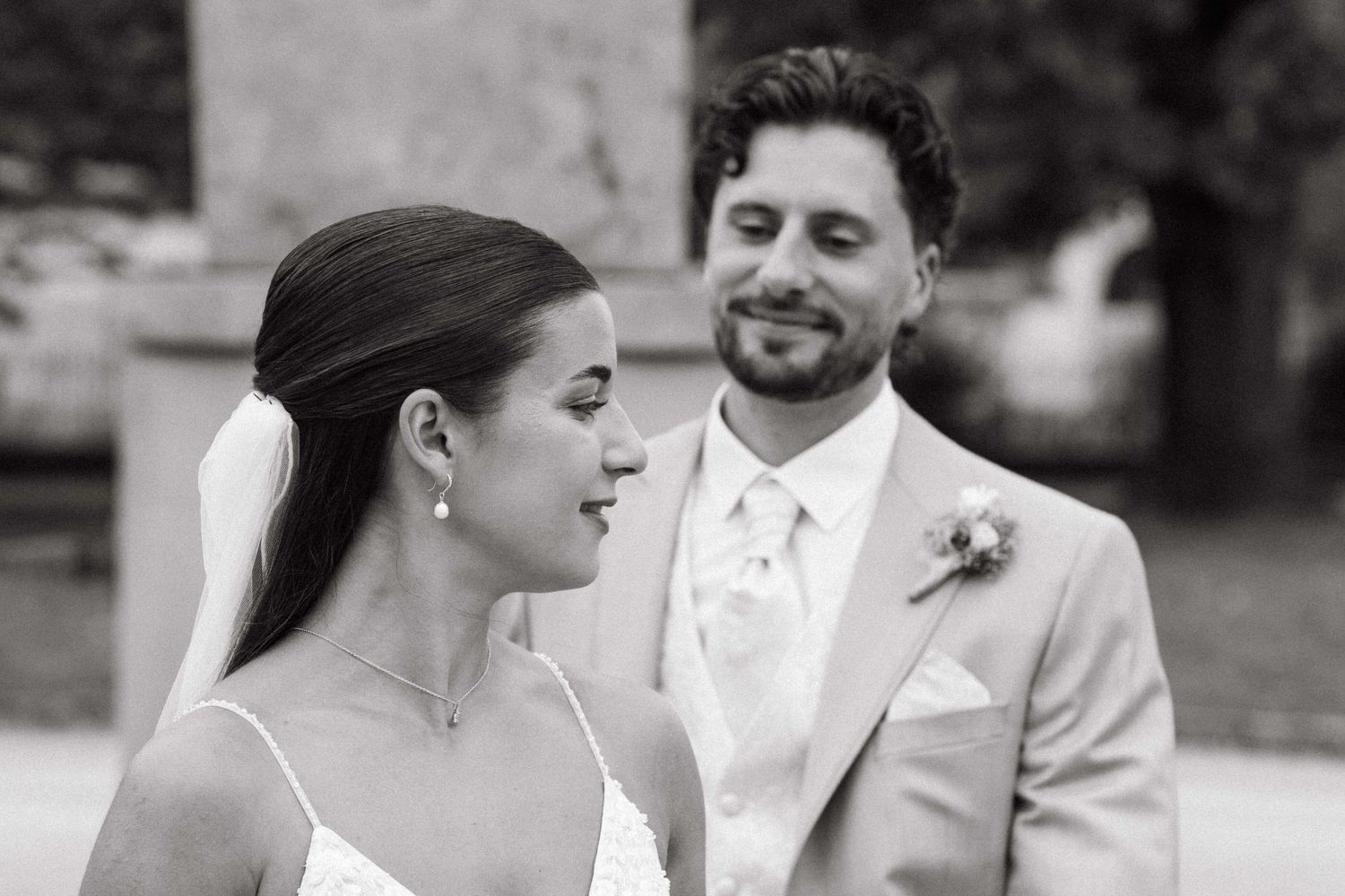 Black and white portrait of bride and groom sharing a tender moment outdoors.