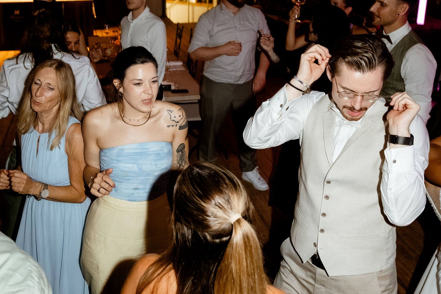 Wedding guests dancing and celebrating on the dance floor at a lively wedding reception.