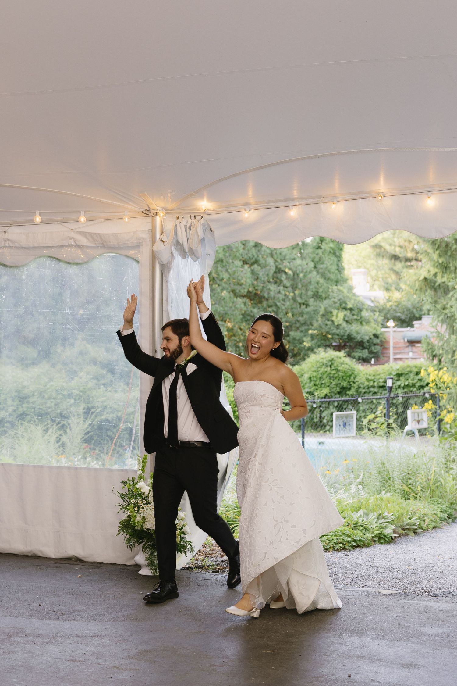 Bride and groom cheer during their reception entrance under the tent at Wadsworth Homestead in Geneseo, NY.