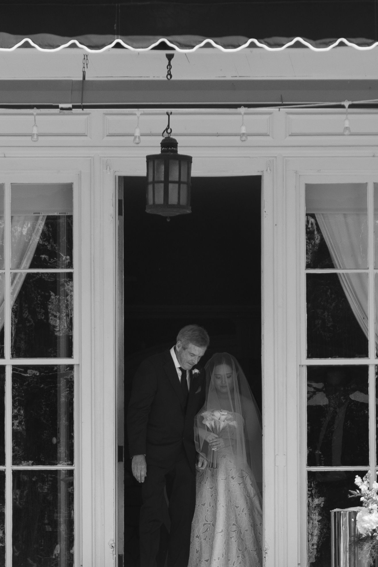 Black and white candid of bride and her father stepping through double doors at Wadsworth Homestead in Geneseo, NY.