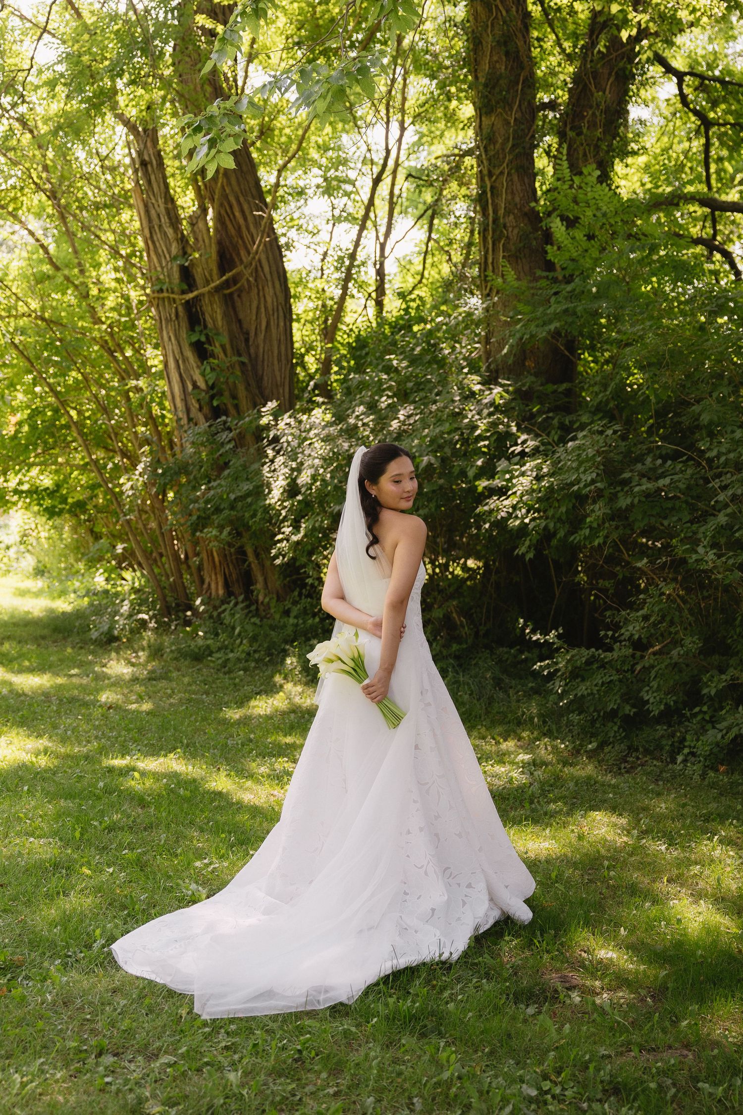 Portrait of bride holding a bouquet of white calla lilies behind her back at Wadsworth Homestead in Geneseo, NY.