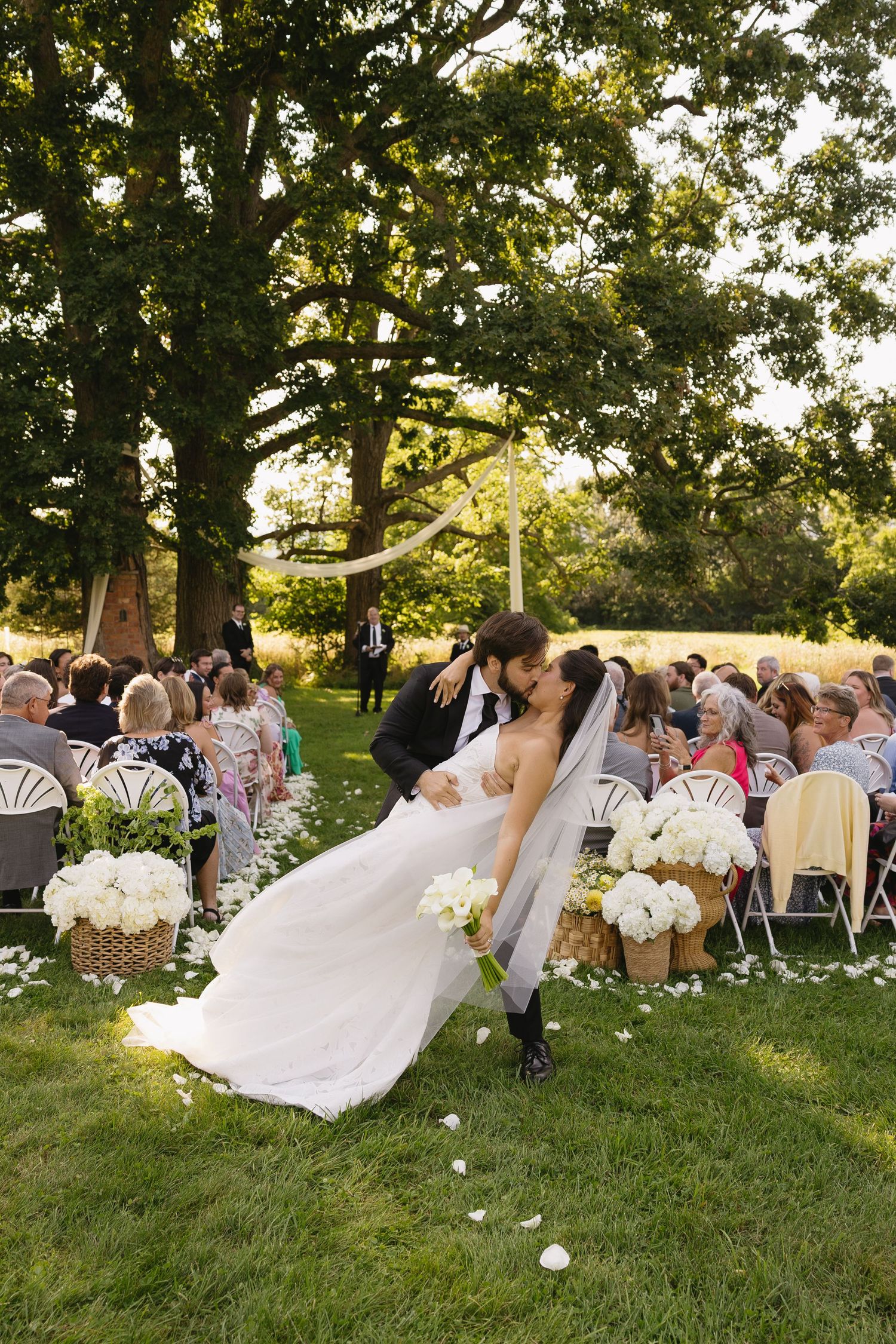 Groom dipping and kissing bride down the aisle at an outdoor ceremony at Wadsworth Homestead in Geneseo, NY.