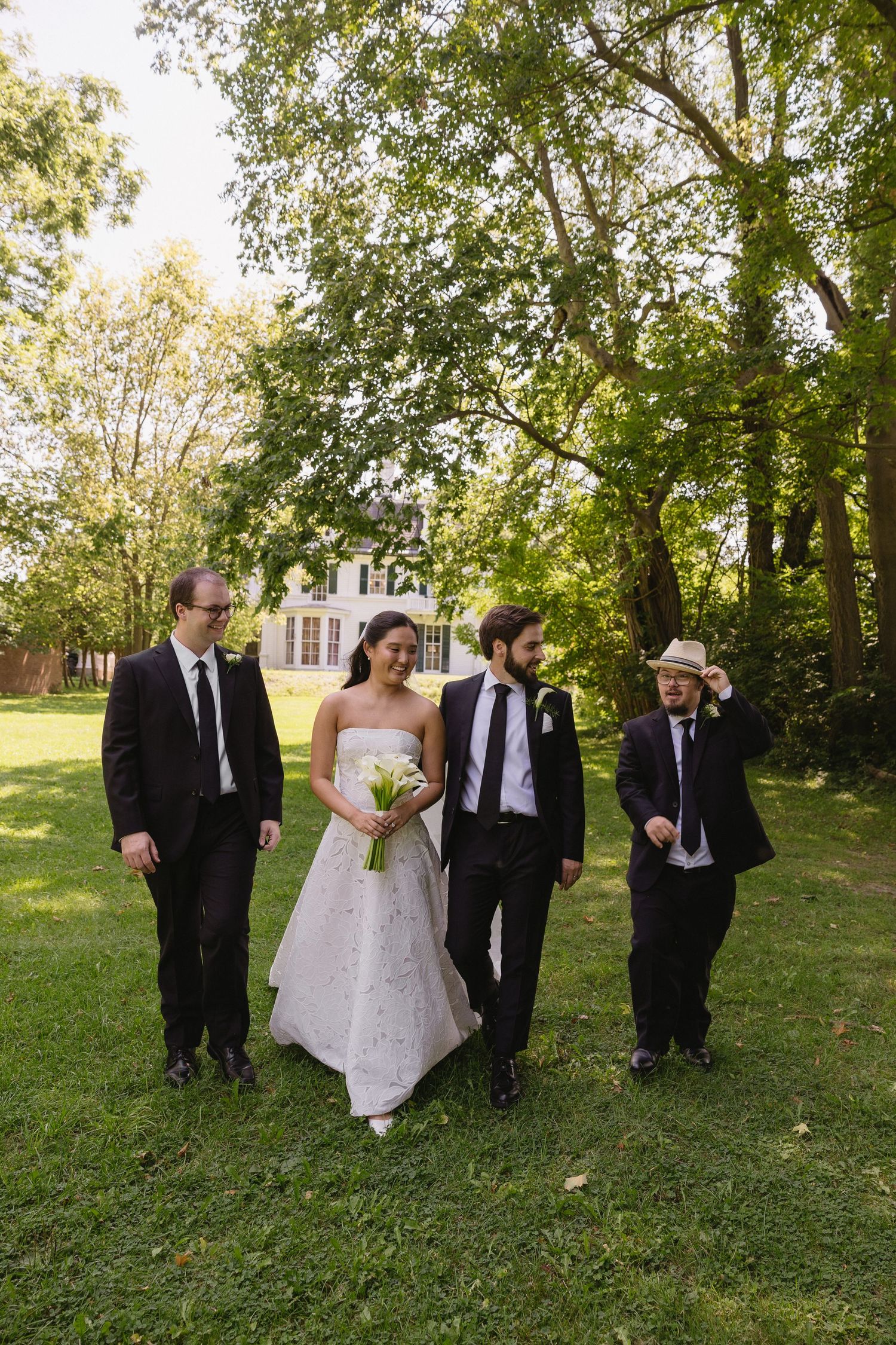 Bride and groom walking on lawn with groomsmen at Wadsworth Homestead in Geneseo, NY.