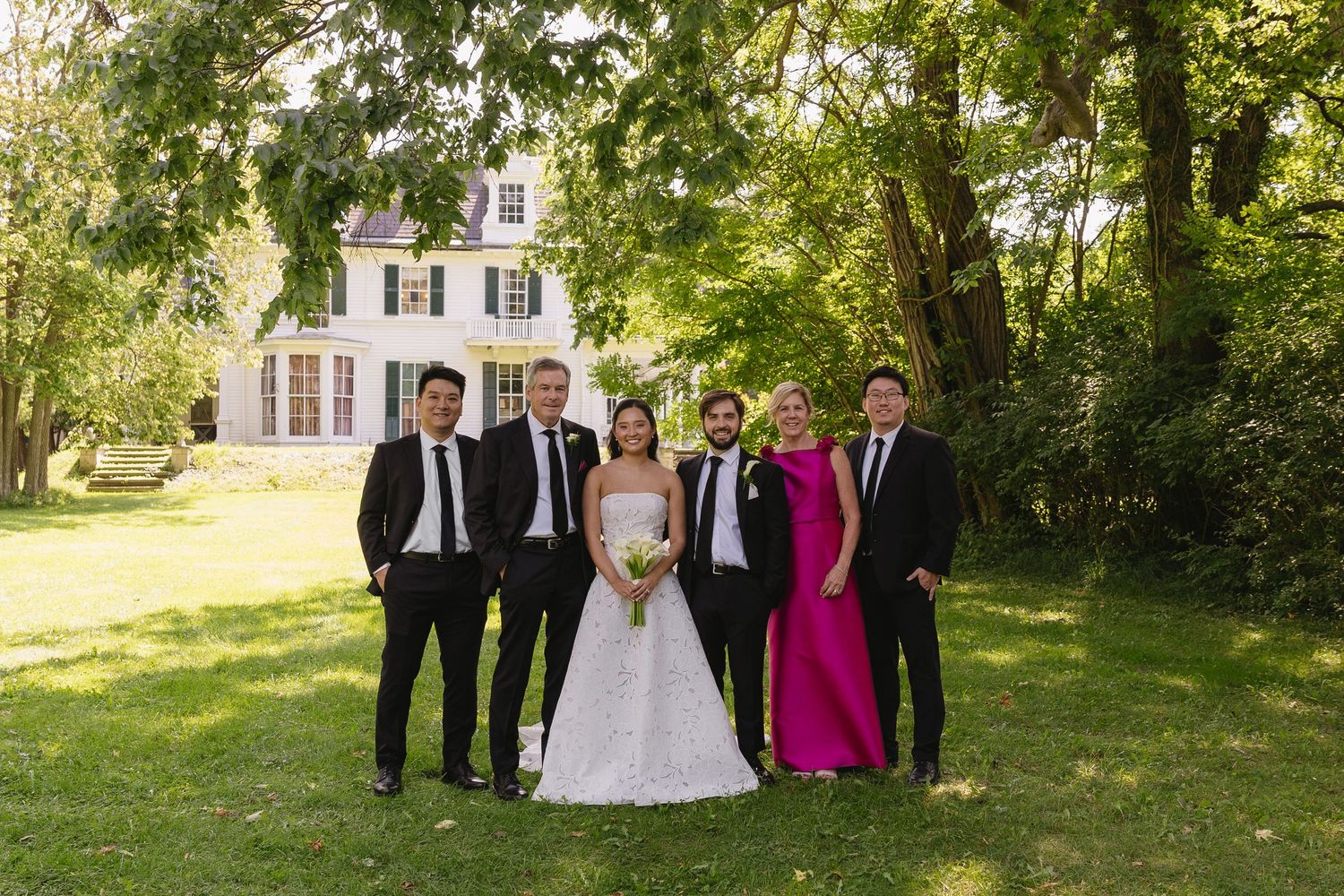 Bride and groom posing with family on the grounds outside Wadsworth Homestead in Geneseo, NY.